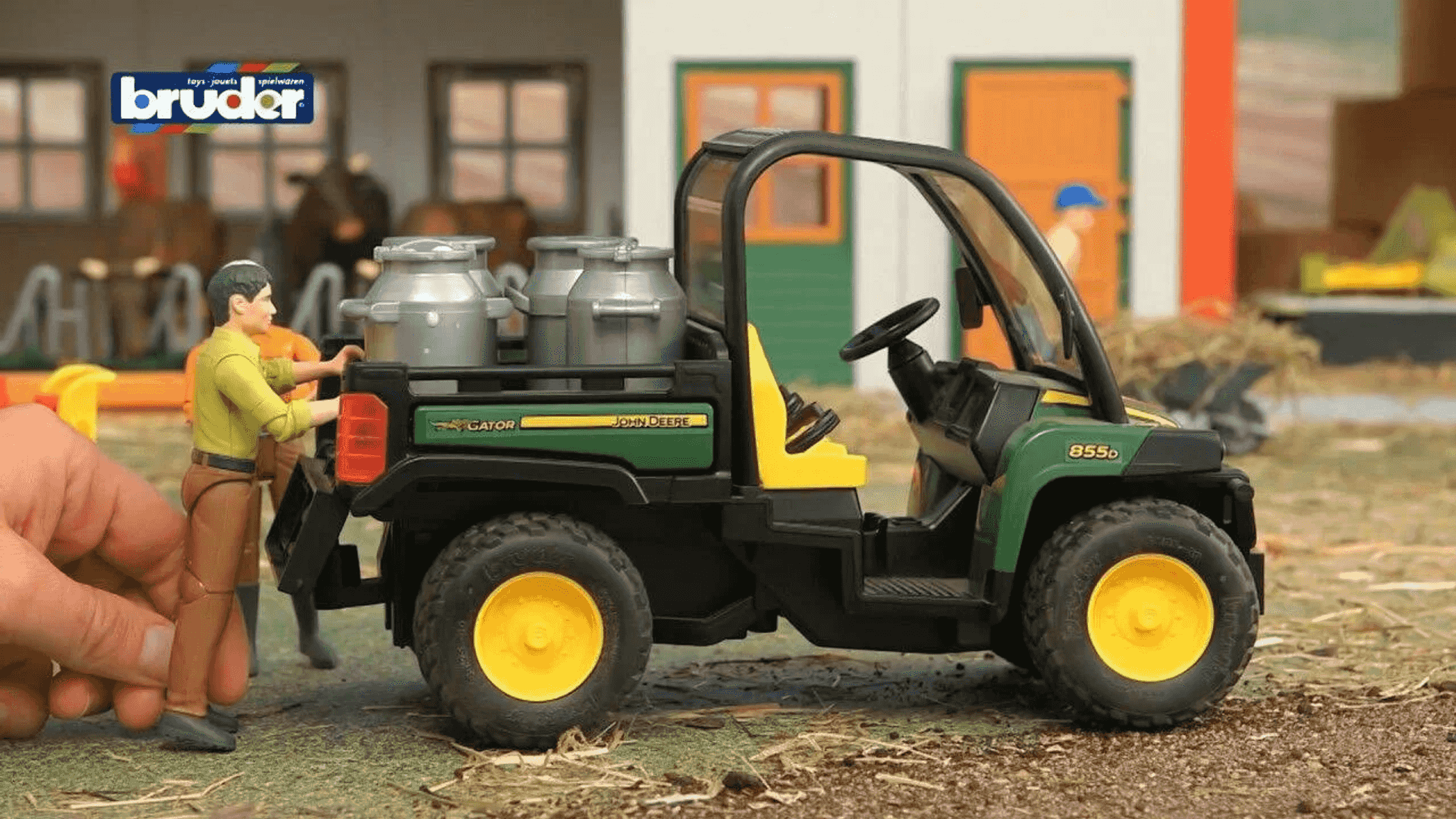 Ein Spielzeug-John-Deere-Gator mit Milchkannen wird von Figuren beladen.