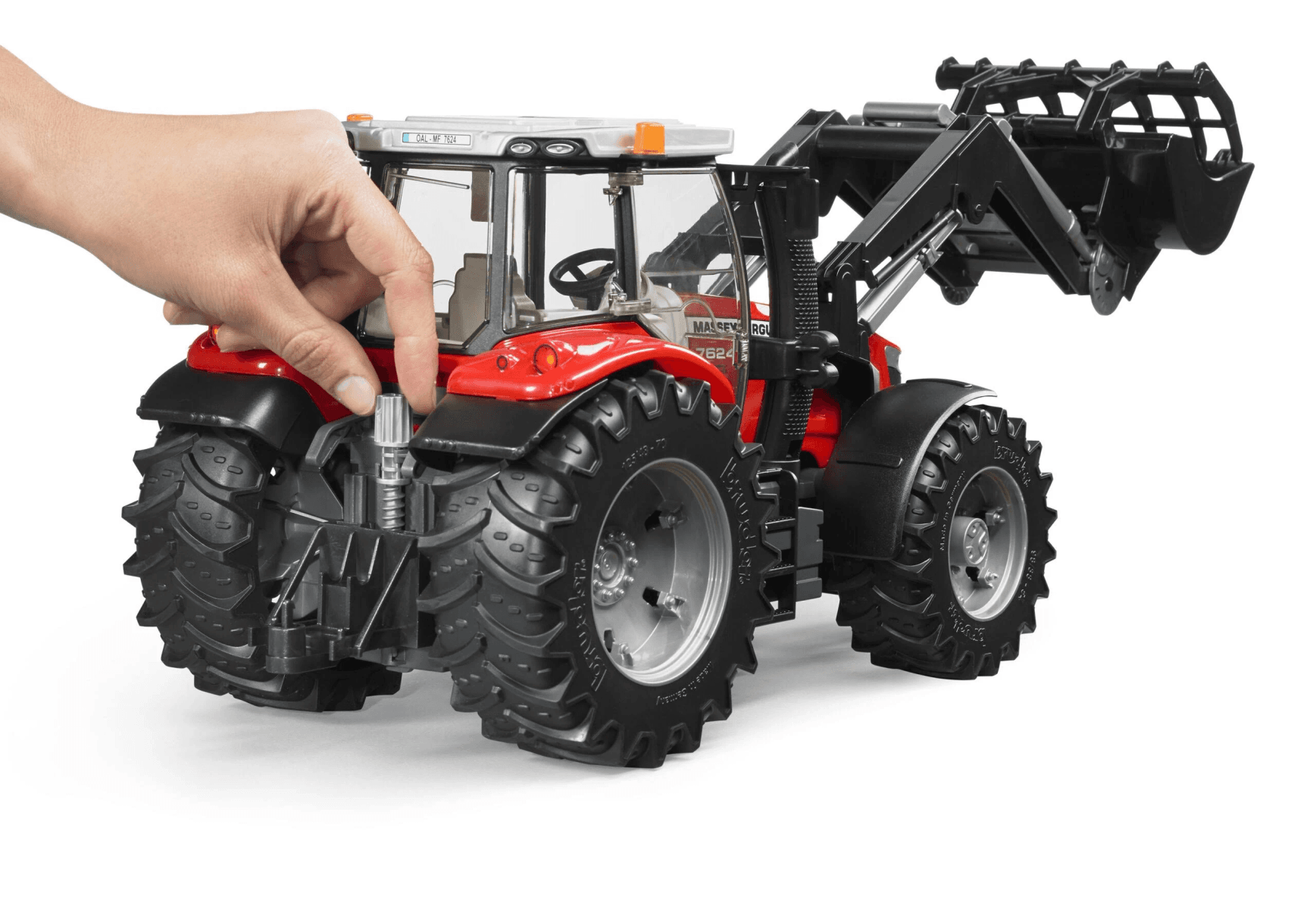 Un tractor de juguete rojo con pala frontal, operado por una mano.