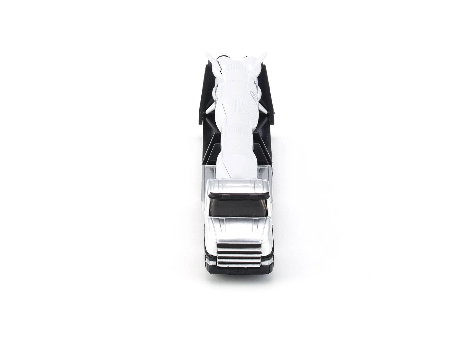 Un camión de juguete plateado transporta una figura alada blanca en su remolque.