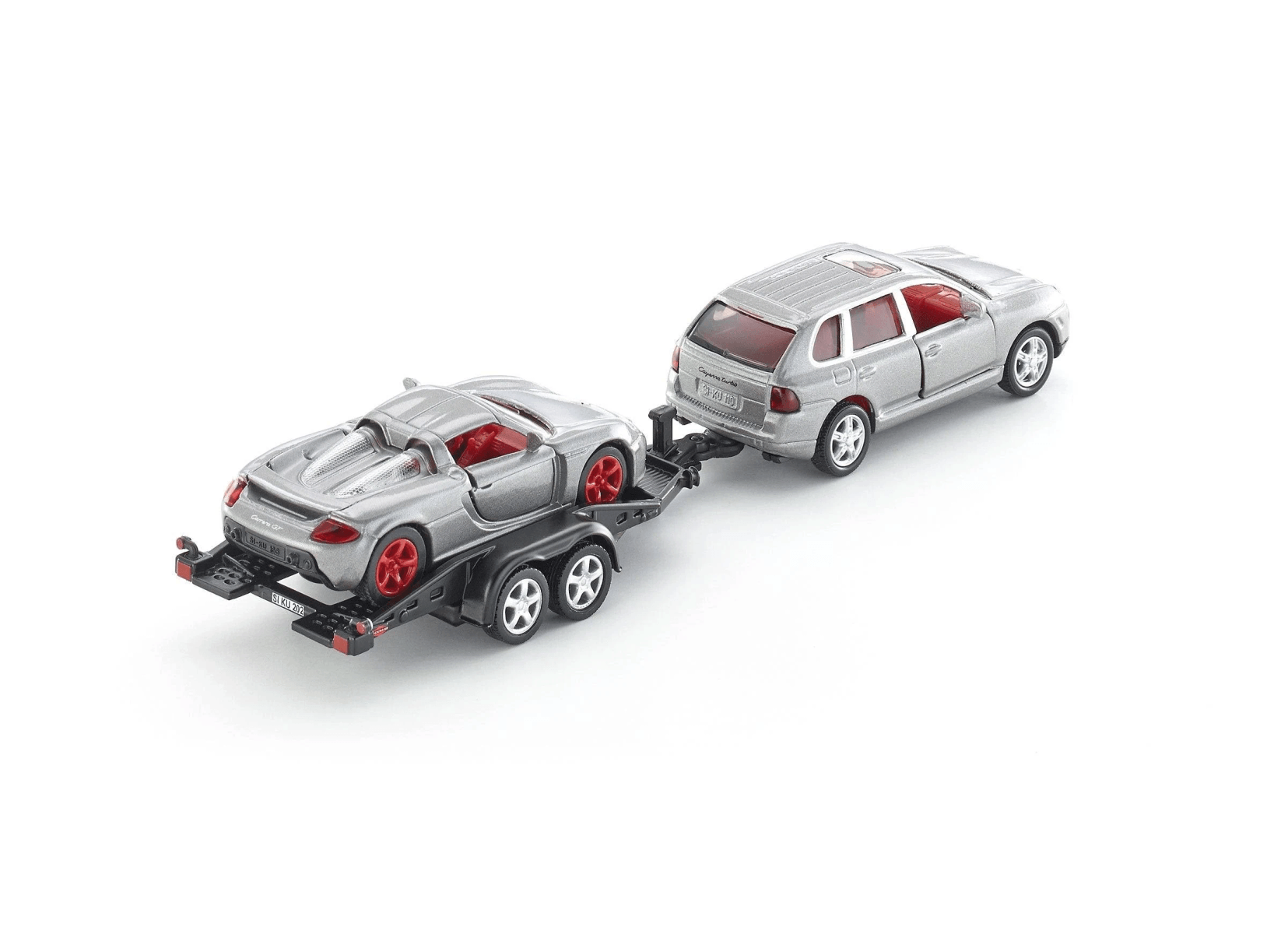 Coche deportivo de juguete plateado en un remolque, remolcado por un SUV plateado.