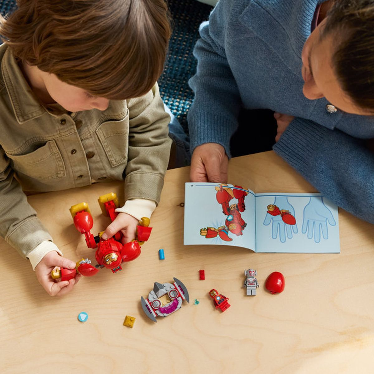 Un bambino costruisce un robot rosso accanto alle istruzioni, una donna guarda.