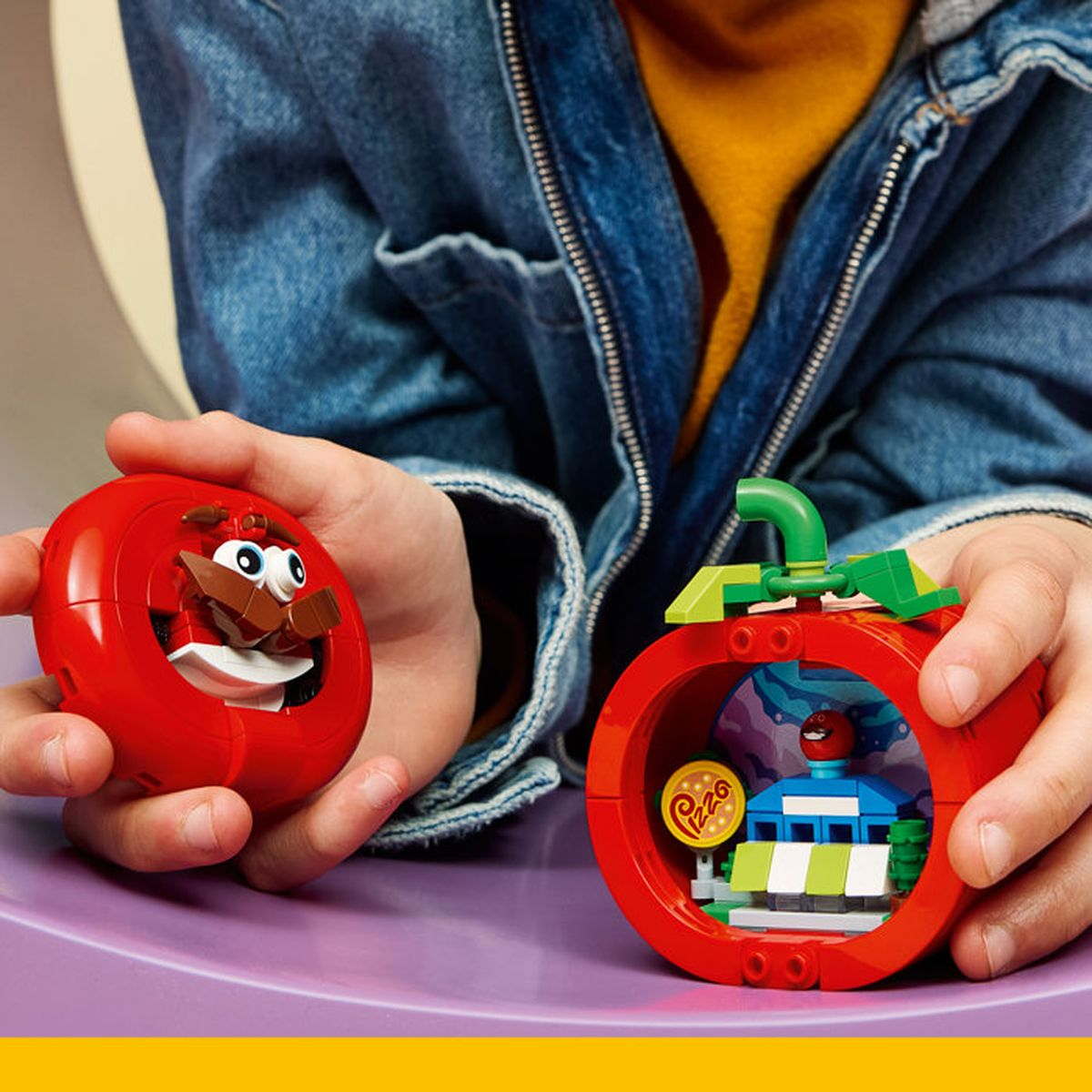 Bambino che tiene giocattoli rossi di pomodoro Lego con figure all'interno.