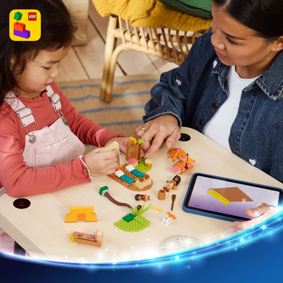Madre e figlia costruiscono giocattoli LEGO al tavolo, con istruzioni su tablet.