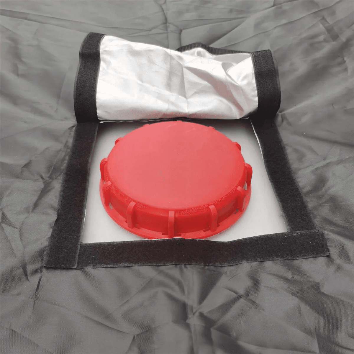 Se ve una tapa roja sobre tela gris con cierre de velcro.