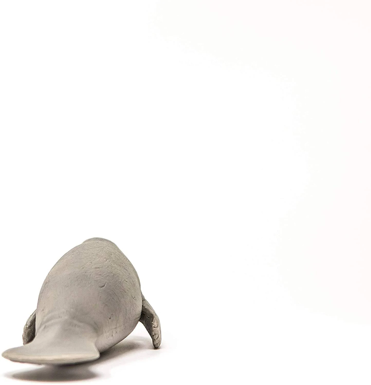 Graue Manati-Figur von hinten auf weißem Grund.