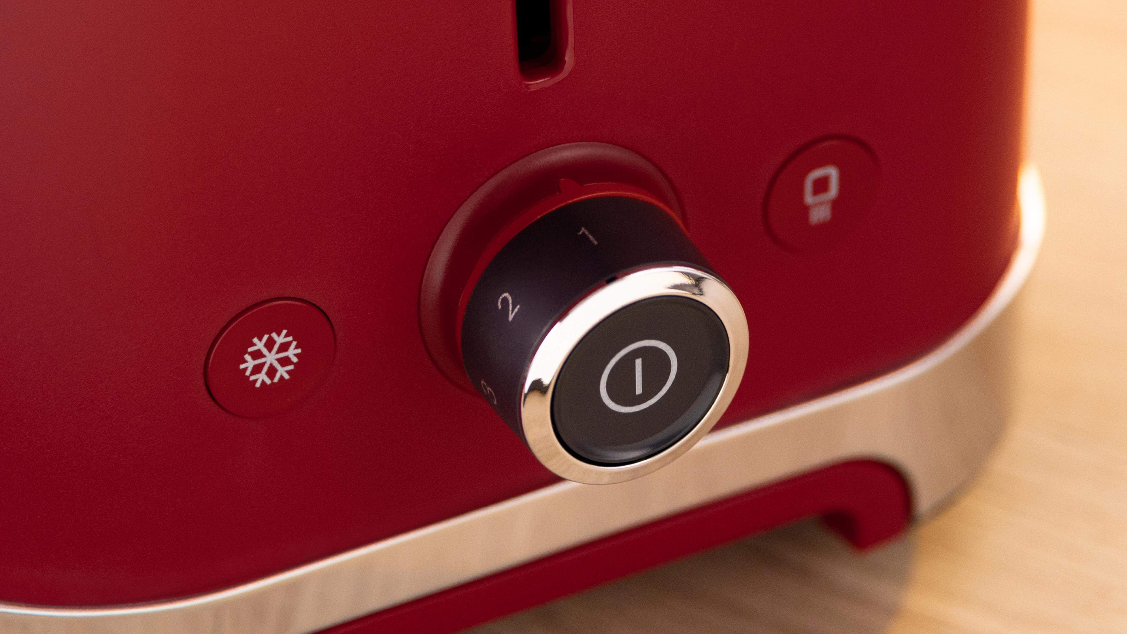 Roter Toaster mit Drehknopf und Symbolen für Kälte und Start.