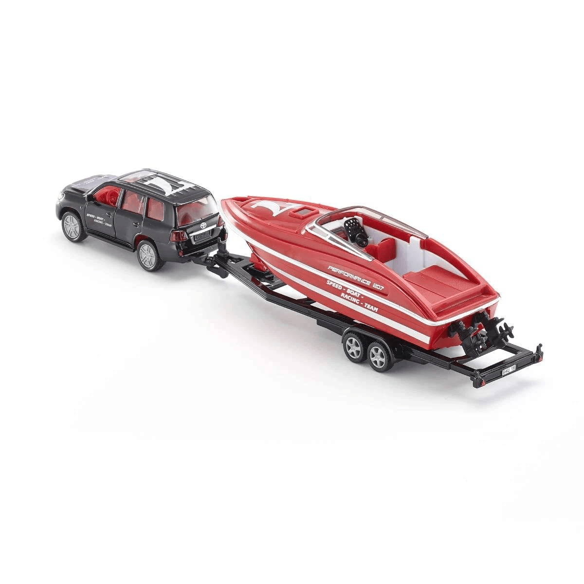 Un coche de juguete negro arrastra un bote de juguete rojo en un remolque.