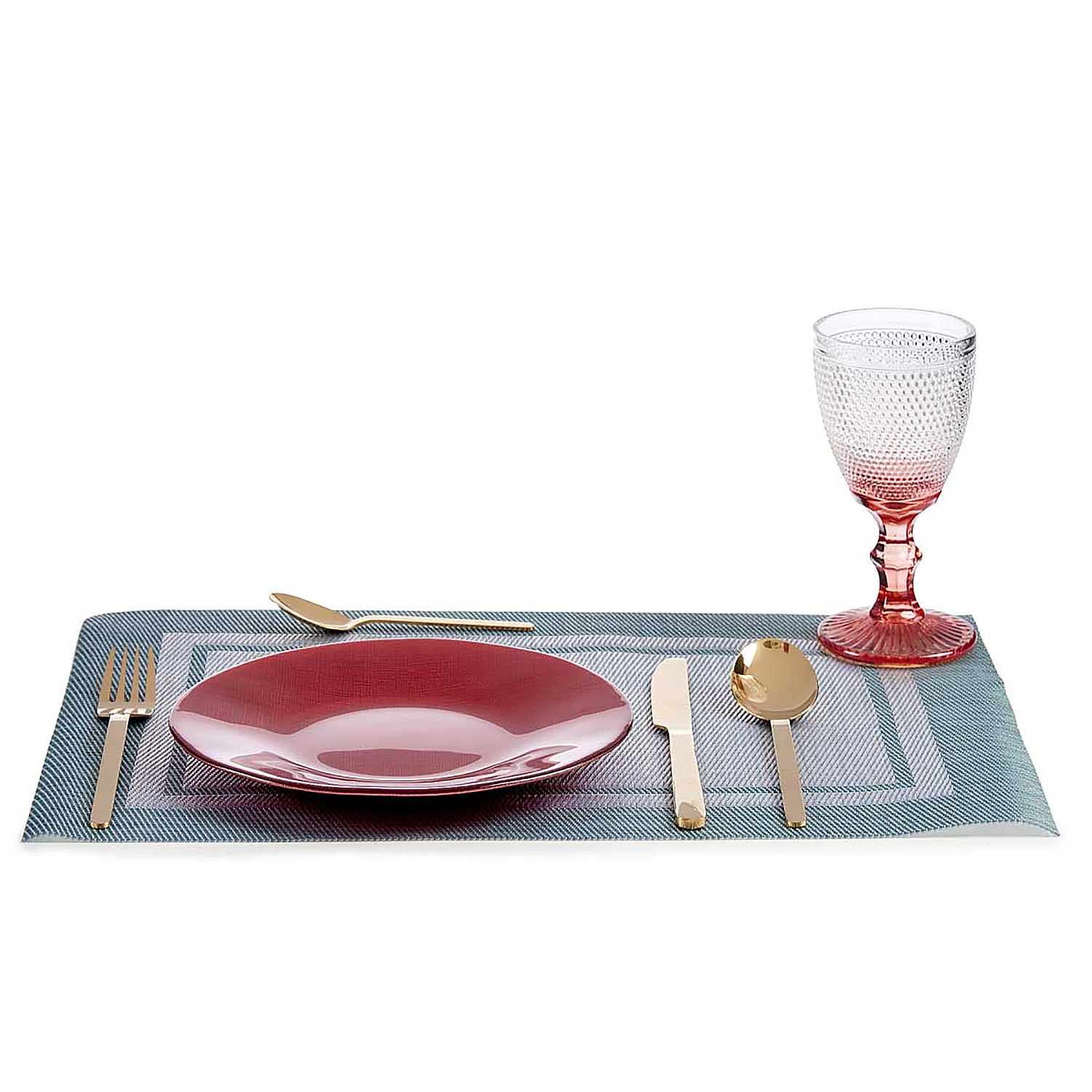 Un'apparecchiatura da tavola con piatto rosso, posate dorate e un bicchiere.