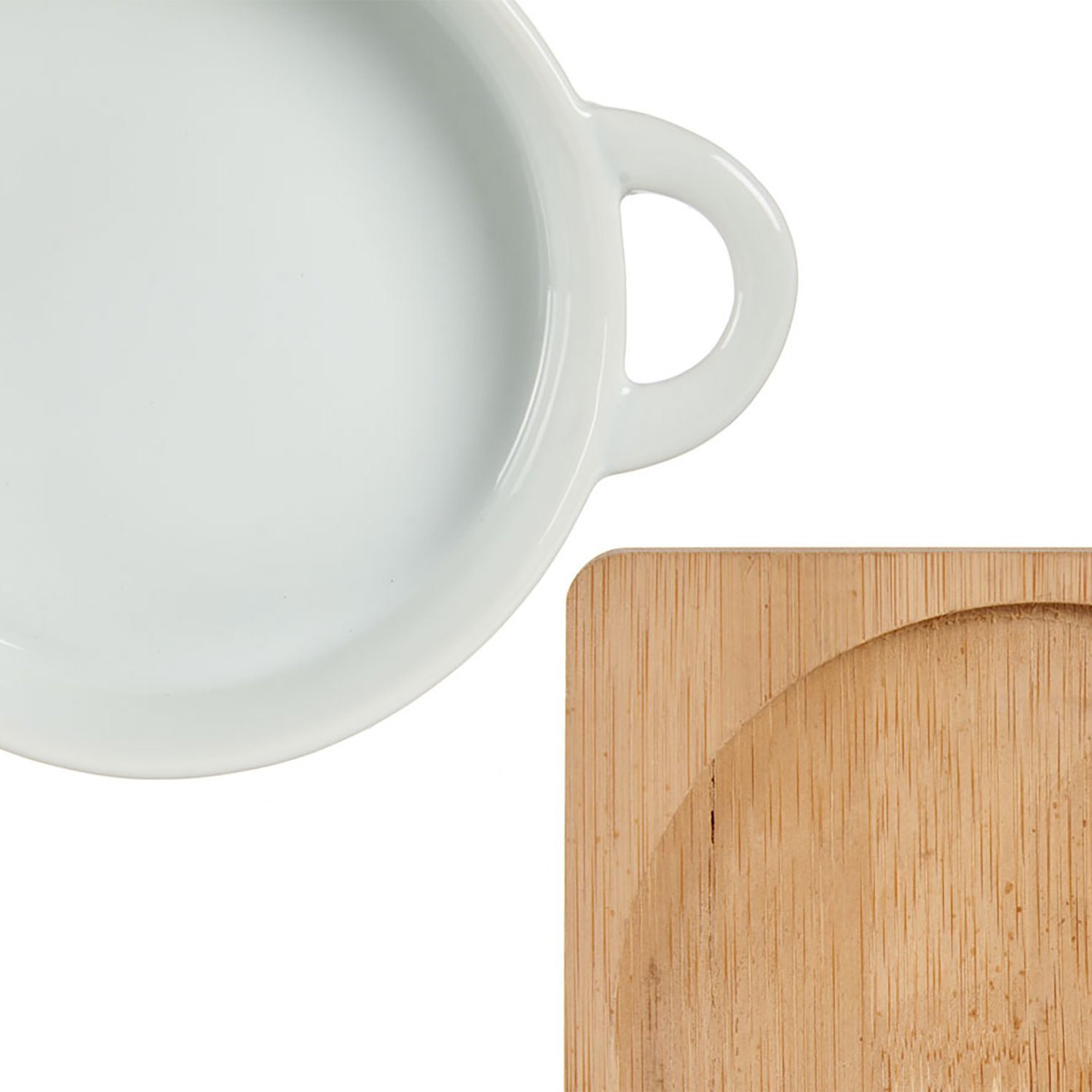 Una ciotola in ceramica bianca con manico accanto a un sottobicchiere di legno.