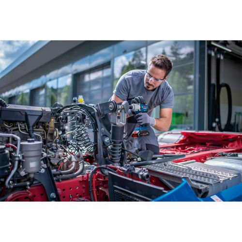Mechanik używa akumulatorowego klucza udarowego do pracy przy silniku ciężarówki.