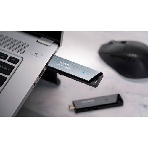 Un'unità USB ADATA argentata collegata a un laptop. Nelle vicinanze si trovano un'unità USB nera e un mouse.