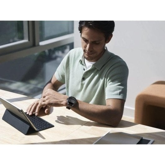 Man with watch at desk typing on a tablet.
