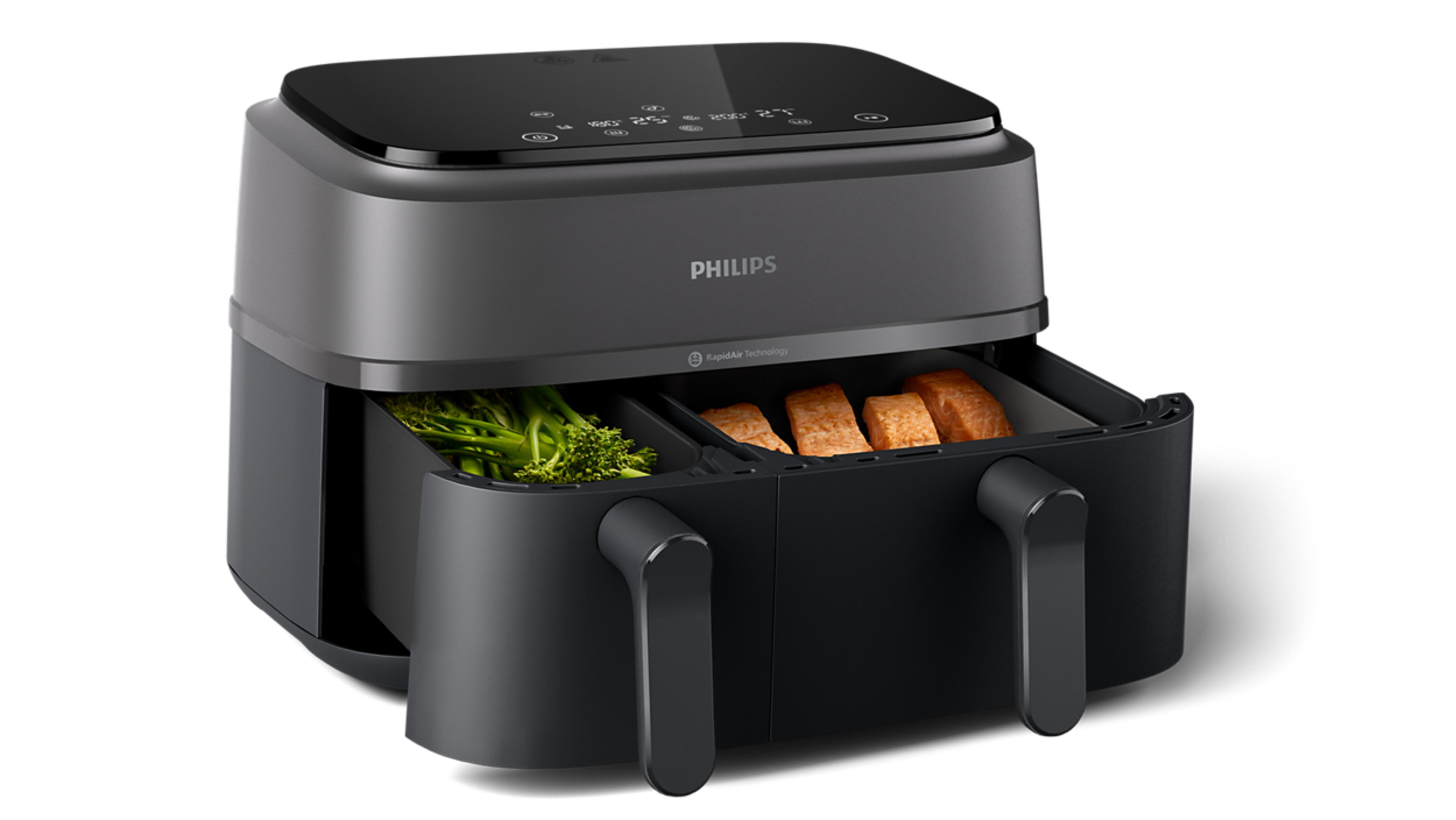Una friggitrice ad aria Philips nera con cestelli doppi, uno con broccoli, l'altro con salmone.
