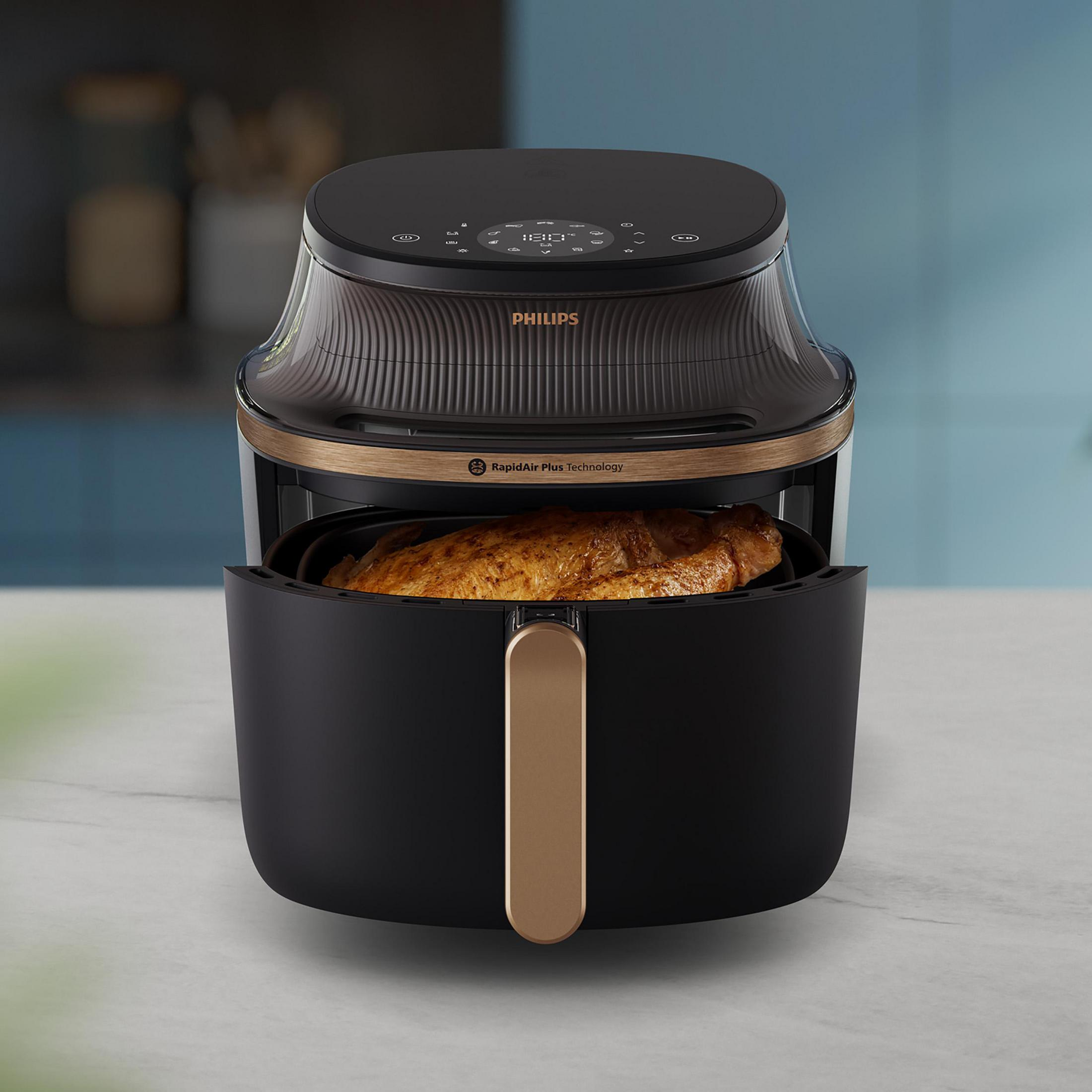 Ein schwarzer Philips Heißluftfritteuse mit einem goldbraunen Brathähnchen darin.