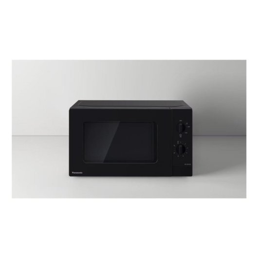 Un forno a microonde Panasonic nero con porta in vetro e manopole di controllo su superficie bianca.