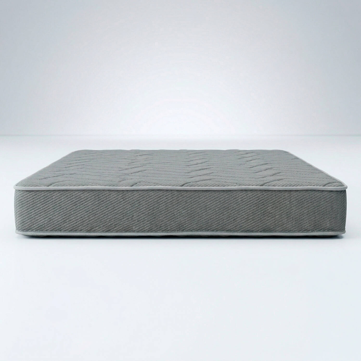 Colchón gris con patrón de zigzag sobre fondo blanco.