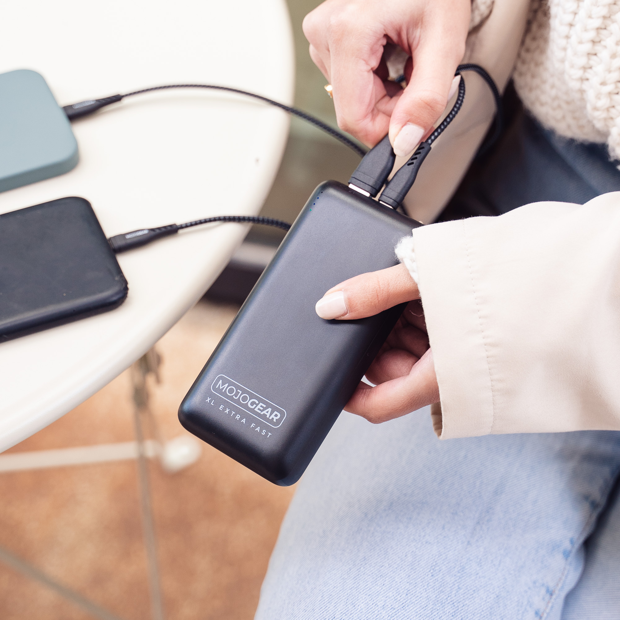 Eine Person schließt Ladekabel an ein schwarzes Powerbank-Gerät an.
