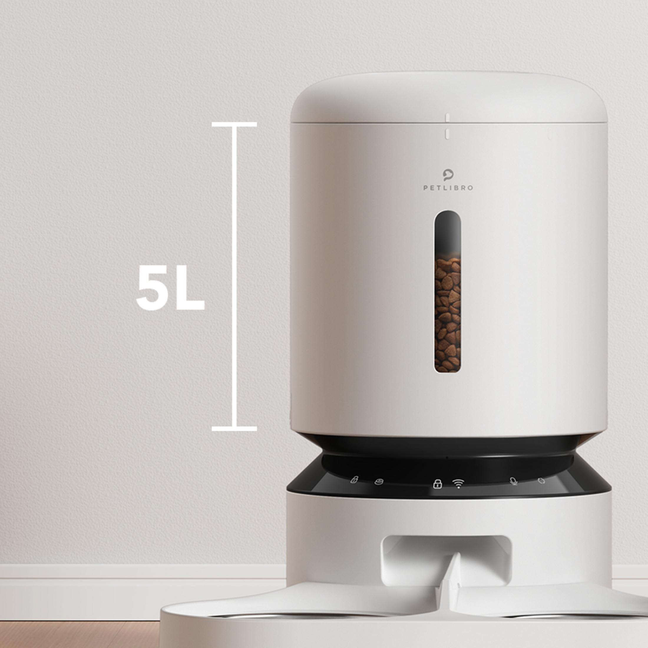 A white 5L automatic pet feeder with food visible in window, on a wooden floor.