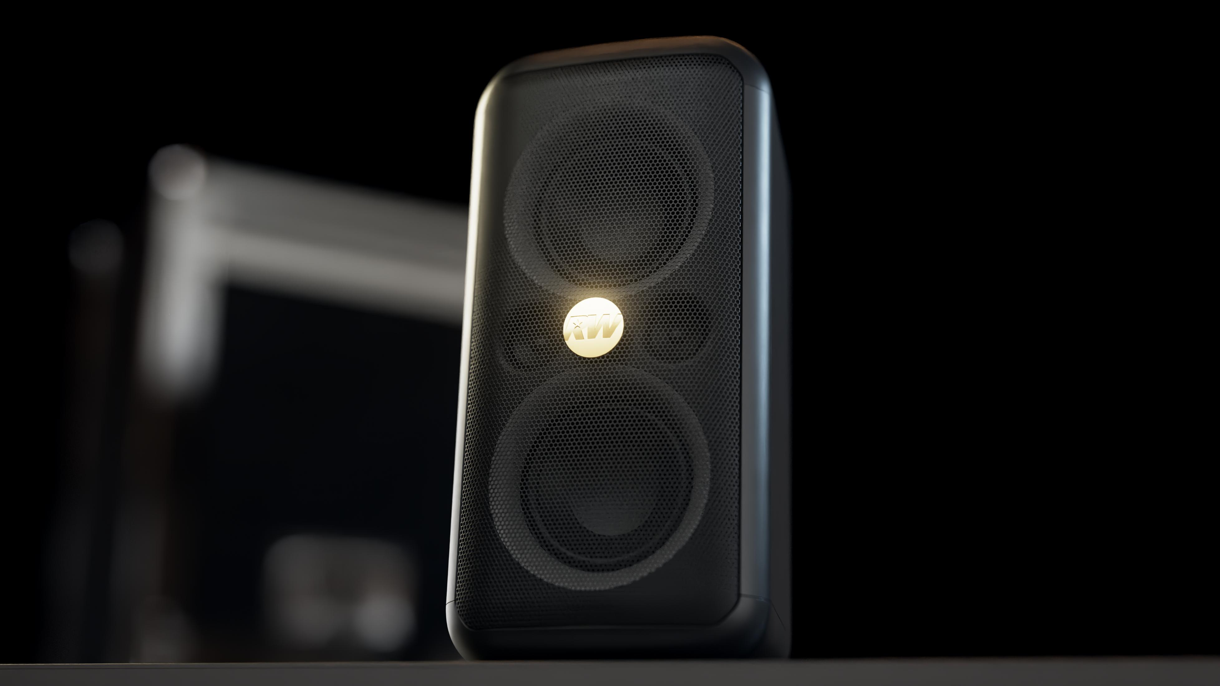 Altavoz negro con logo dorado sobre fondo oscuro.