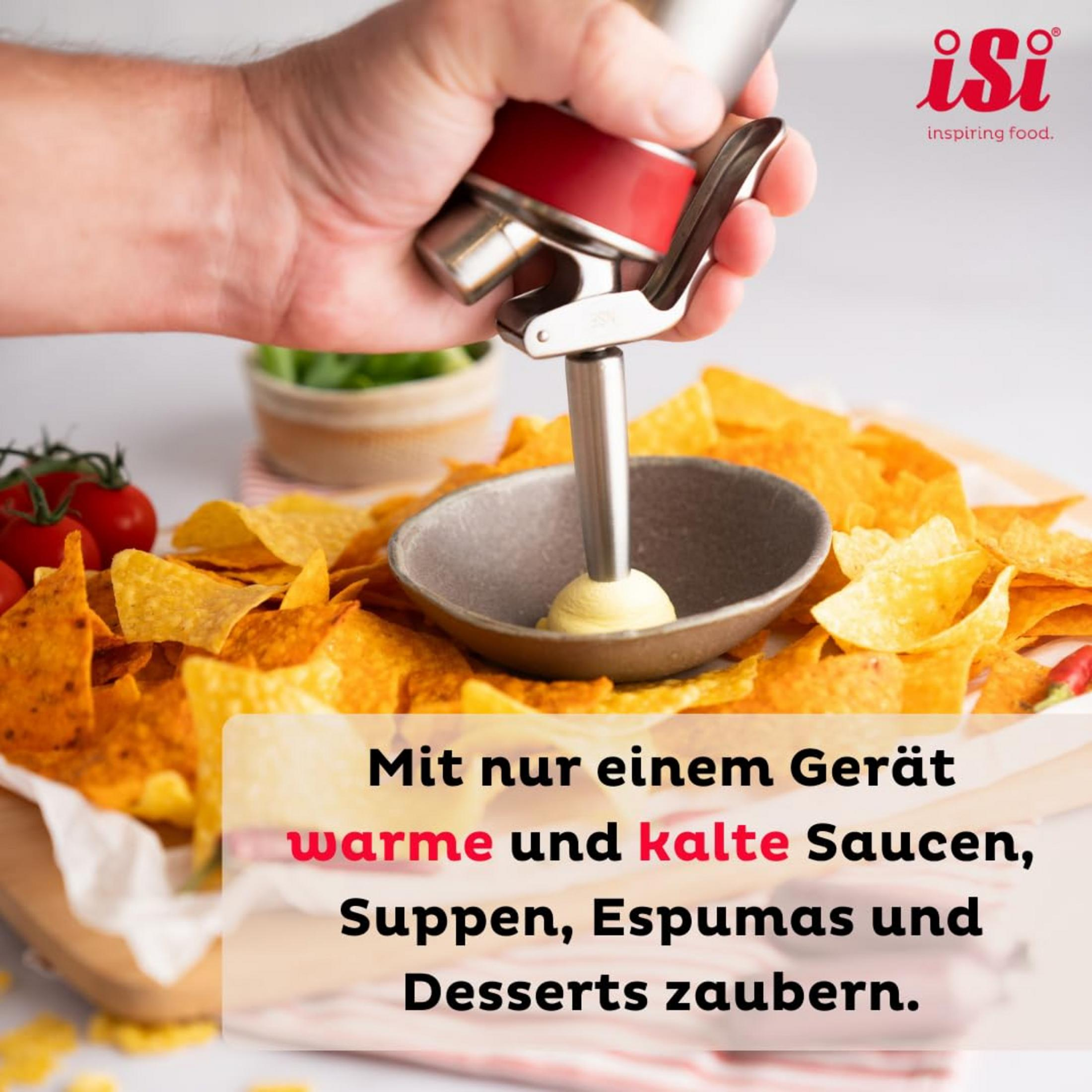 Eine Hand benutzt einen Sahnespender, um eine gelbe Creme auf Nachos zu geben.