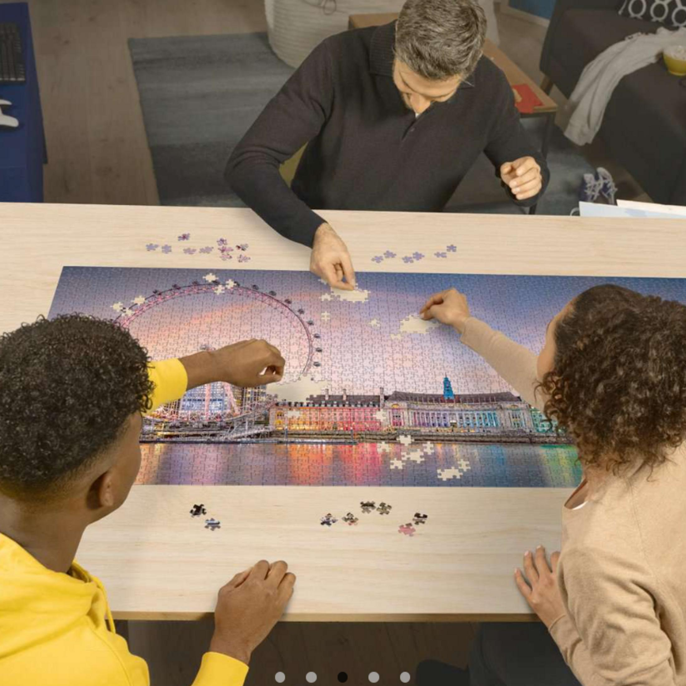 Trois personnes assemblent un puzzle de London Eye et de bâtiments riverains.
