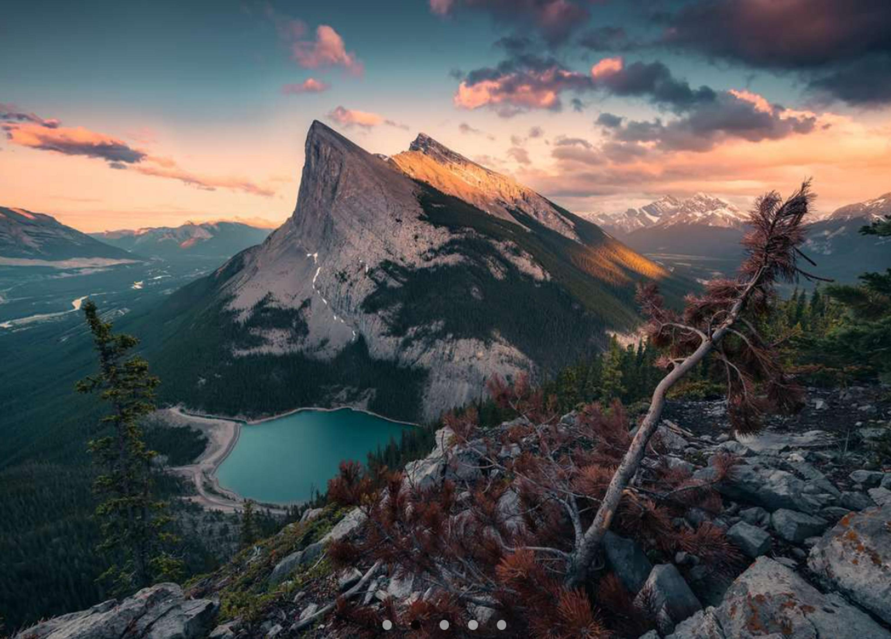 Paysage de montagne au coucher du soleil avec lac et pinède.