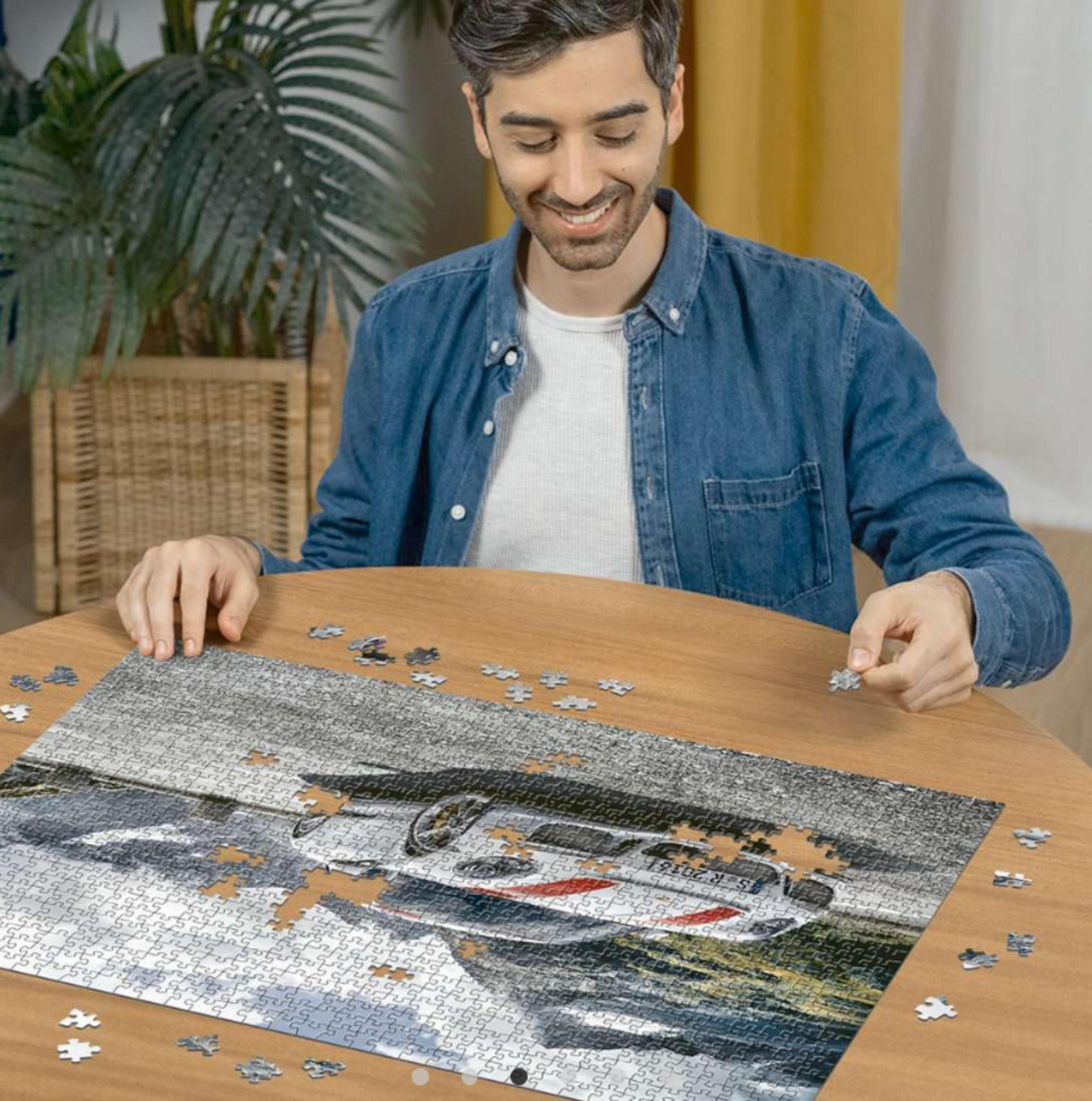 Homme faisant un puzzle de voiture sur une table en bois.