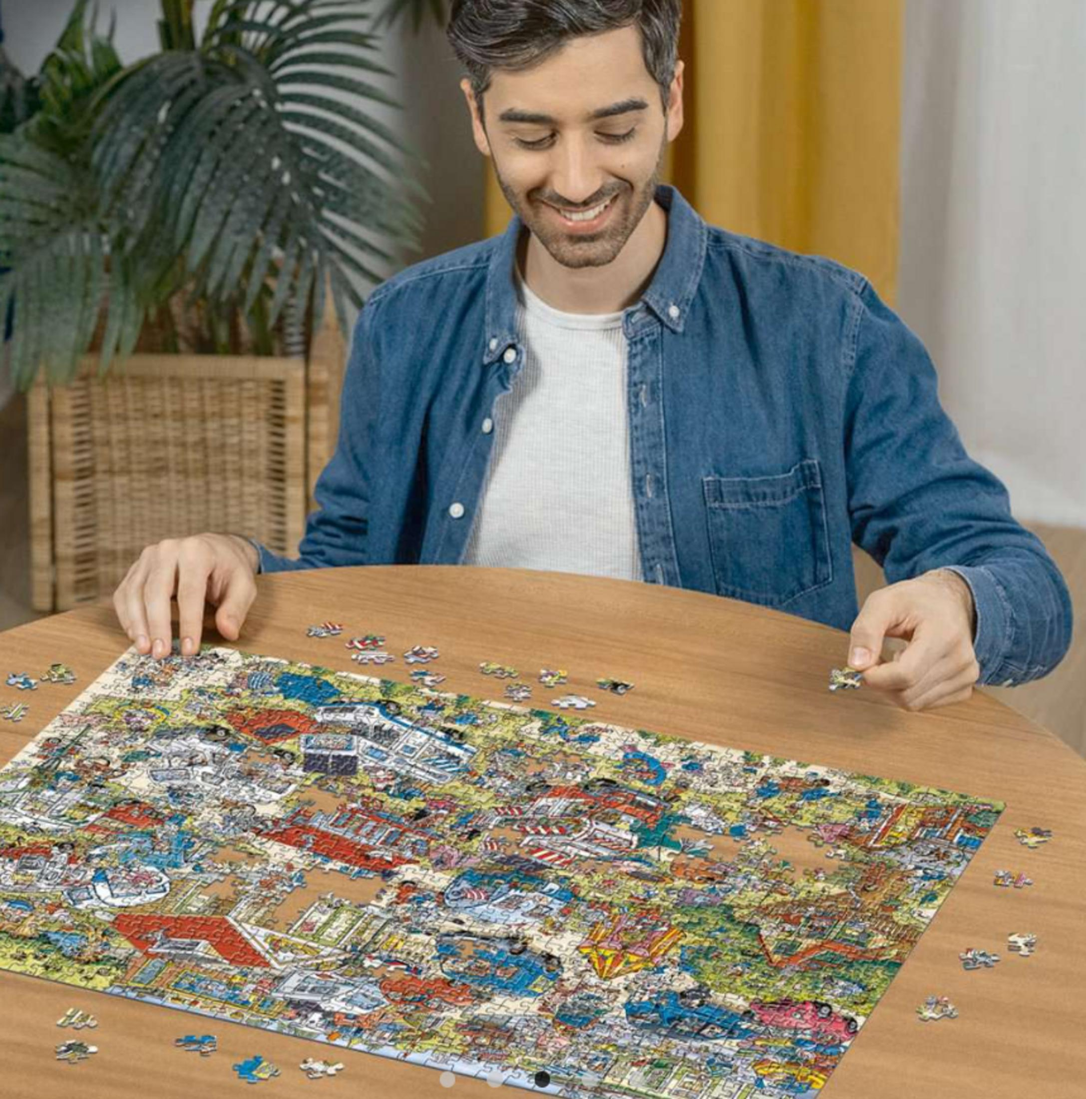 Un uomo seduto a un tavolo di legno aggiunge un pezzo del puzzle. Un puzzle completato è davanti a lui.