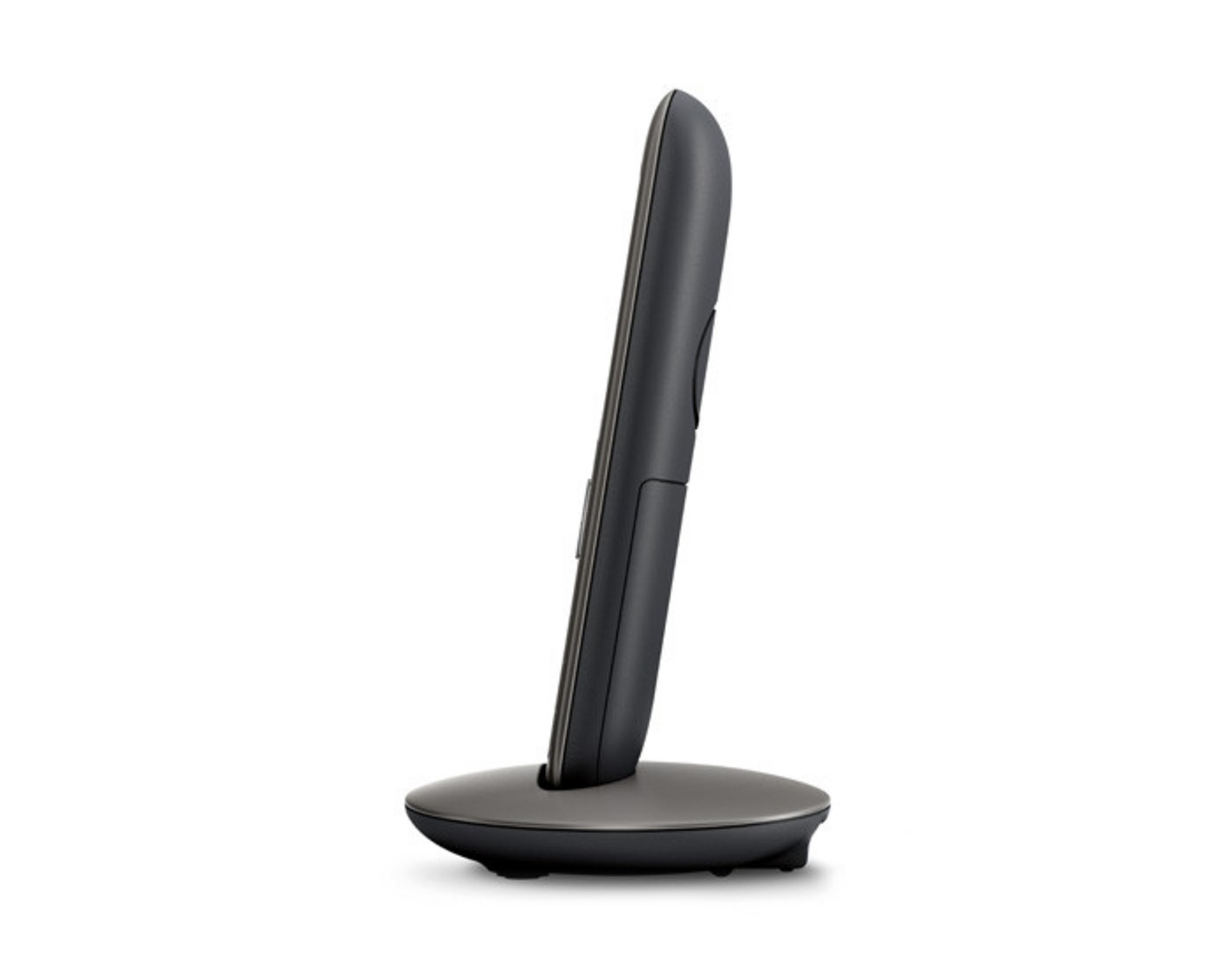 Un telefono cordless scuro poggia sulla sua base di ricarica.