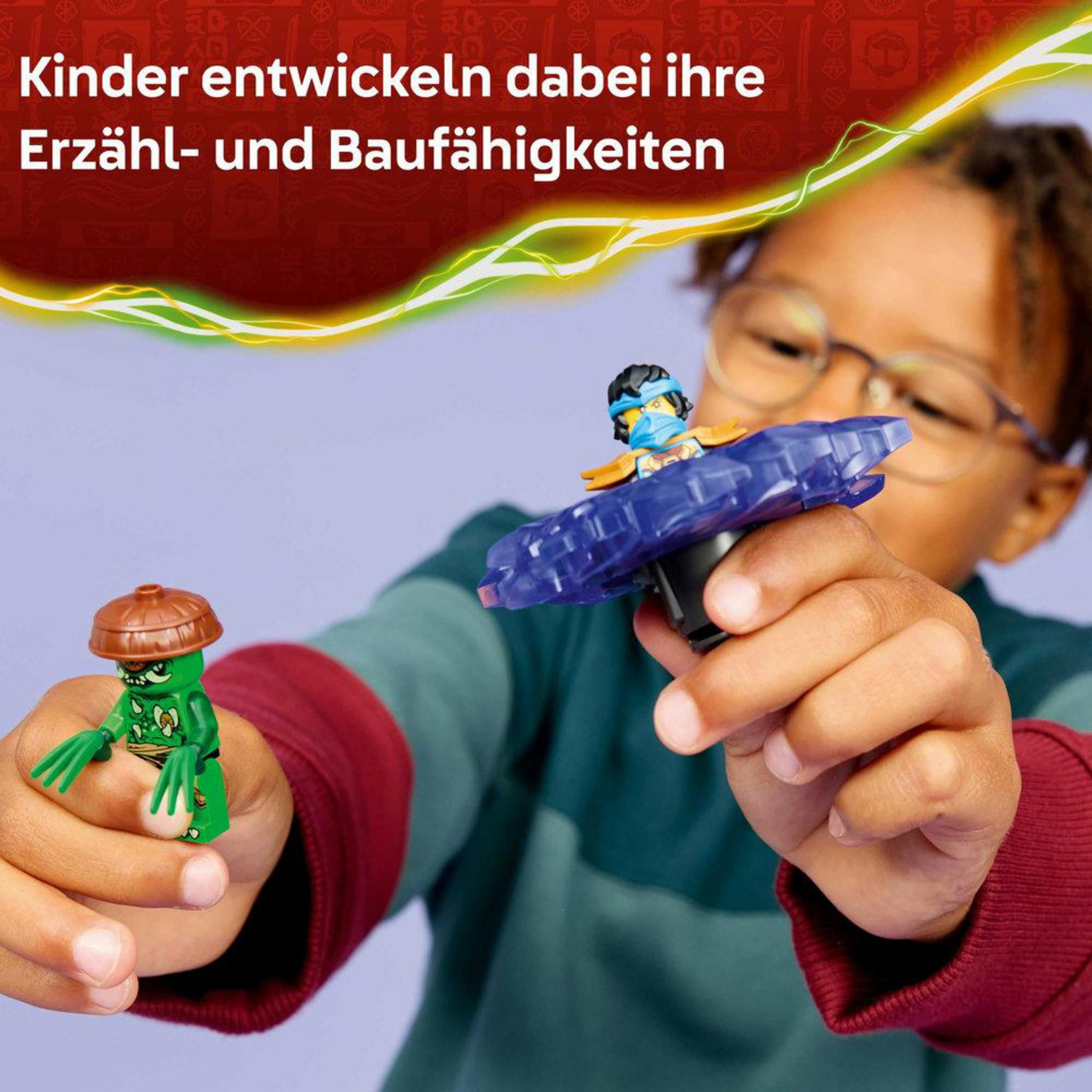 Ein Kind hält zwei Lego-Figuren, eine grüne und eine auf einem blauen Spinnturm.