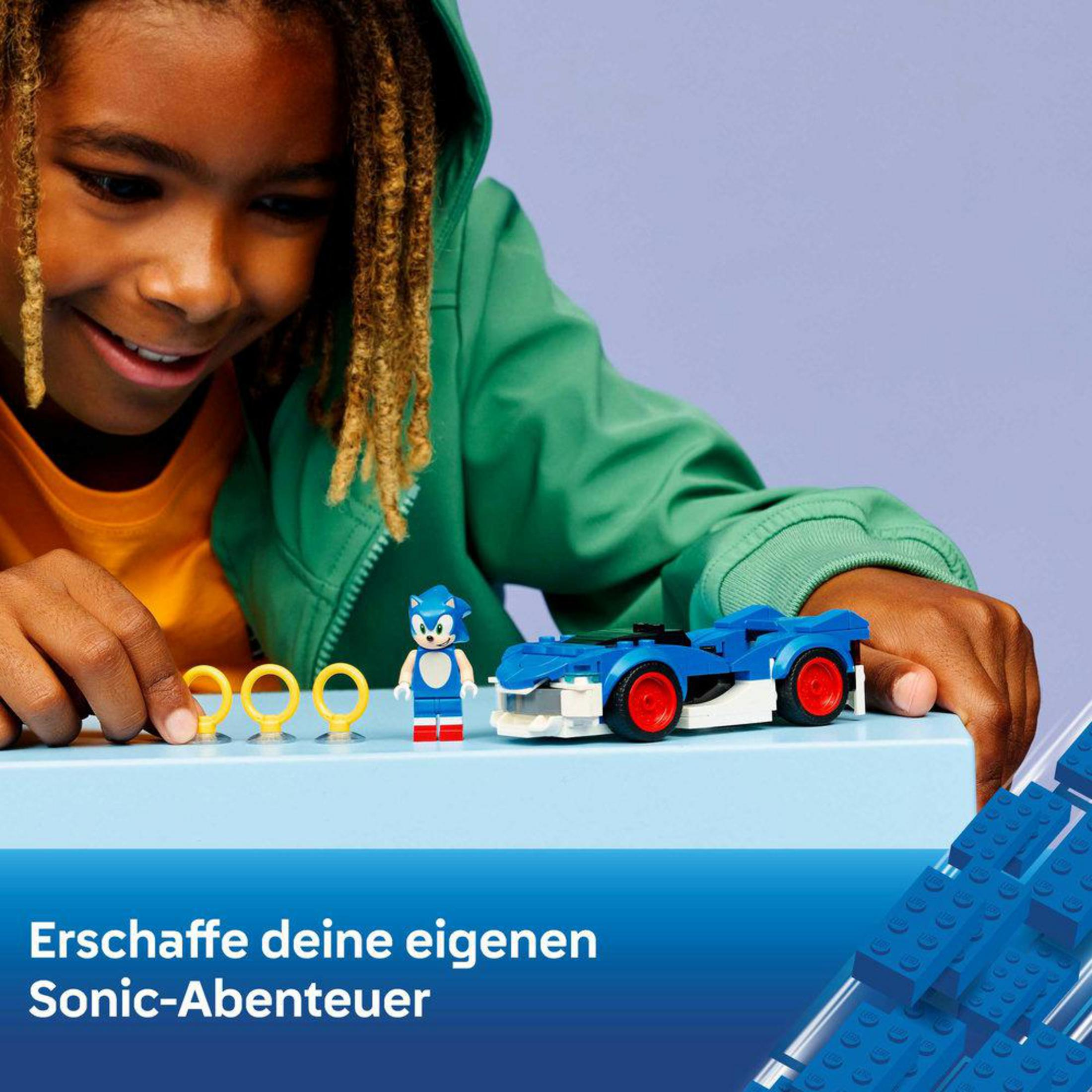 Bir çocuk mavi LEGO araba, Sonic figürü ve yüzüklerle oynuyor.
