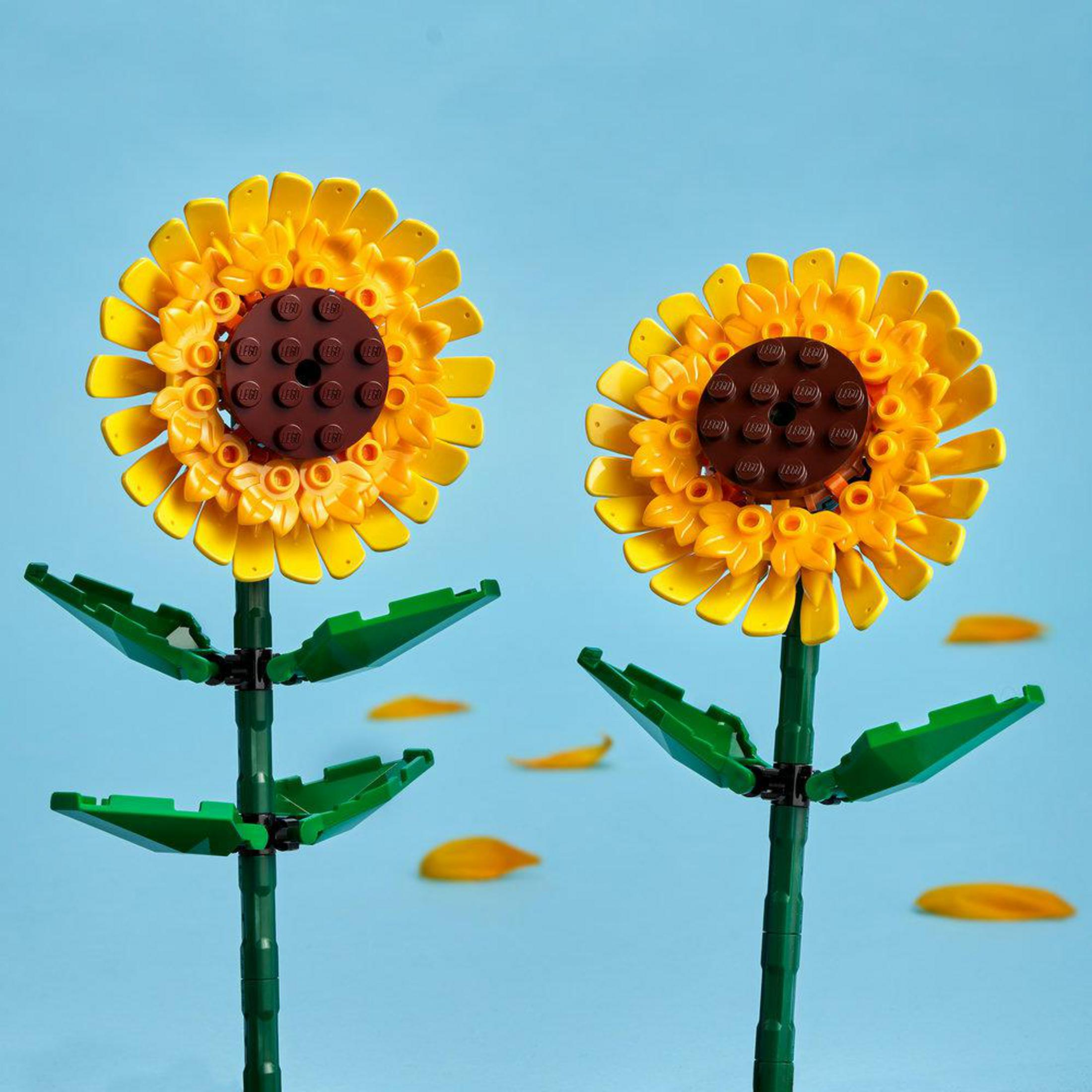 Dos girasoles de LEGO con pétalos amarillos sobre un cielo azul.