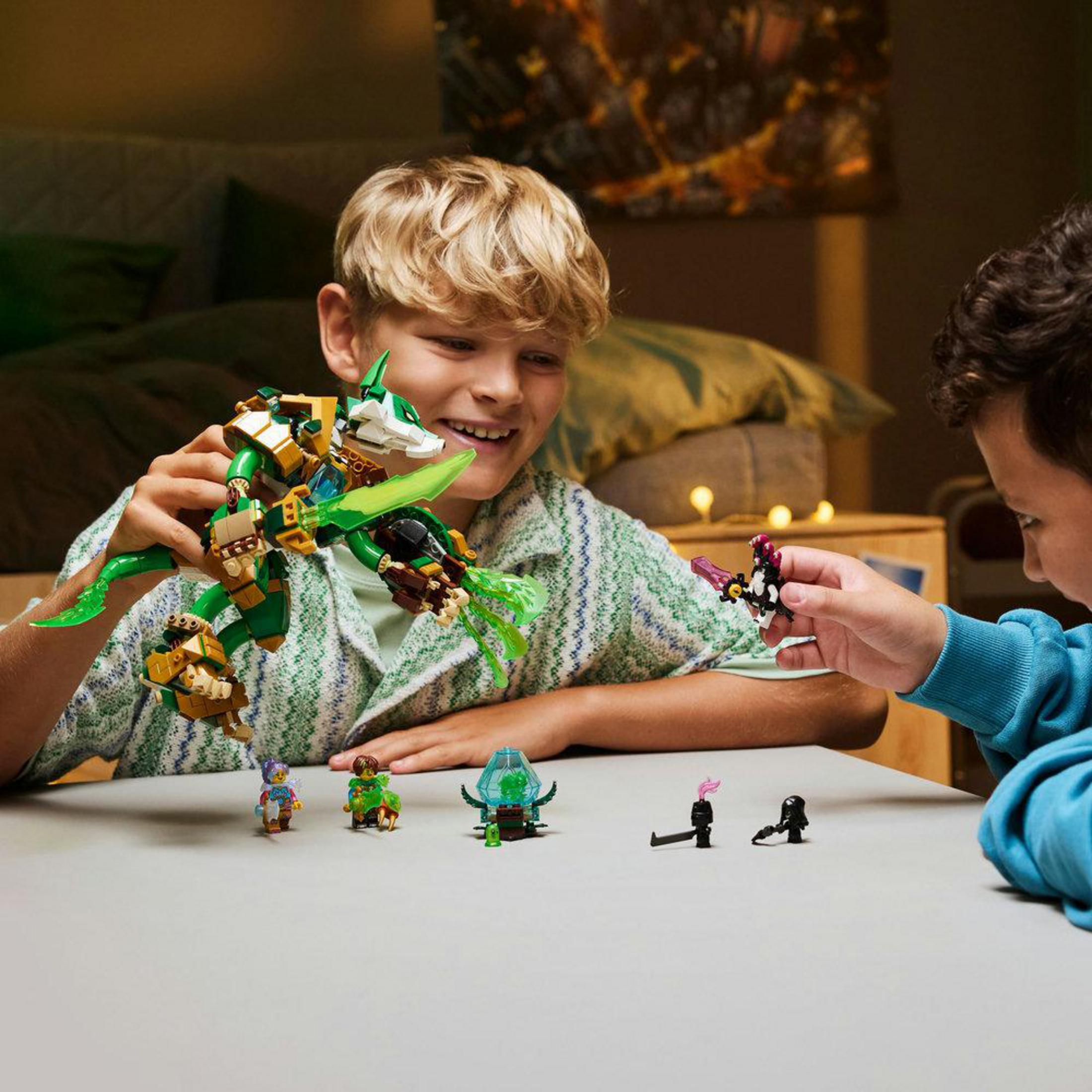 İki çocuk, Lego figürleri ve yeşil ejderha oyuncağıyla oynuyor.