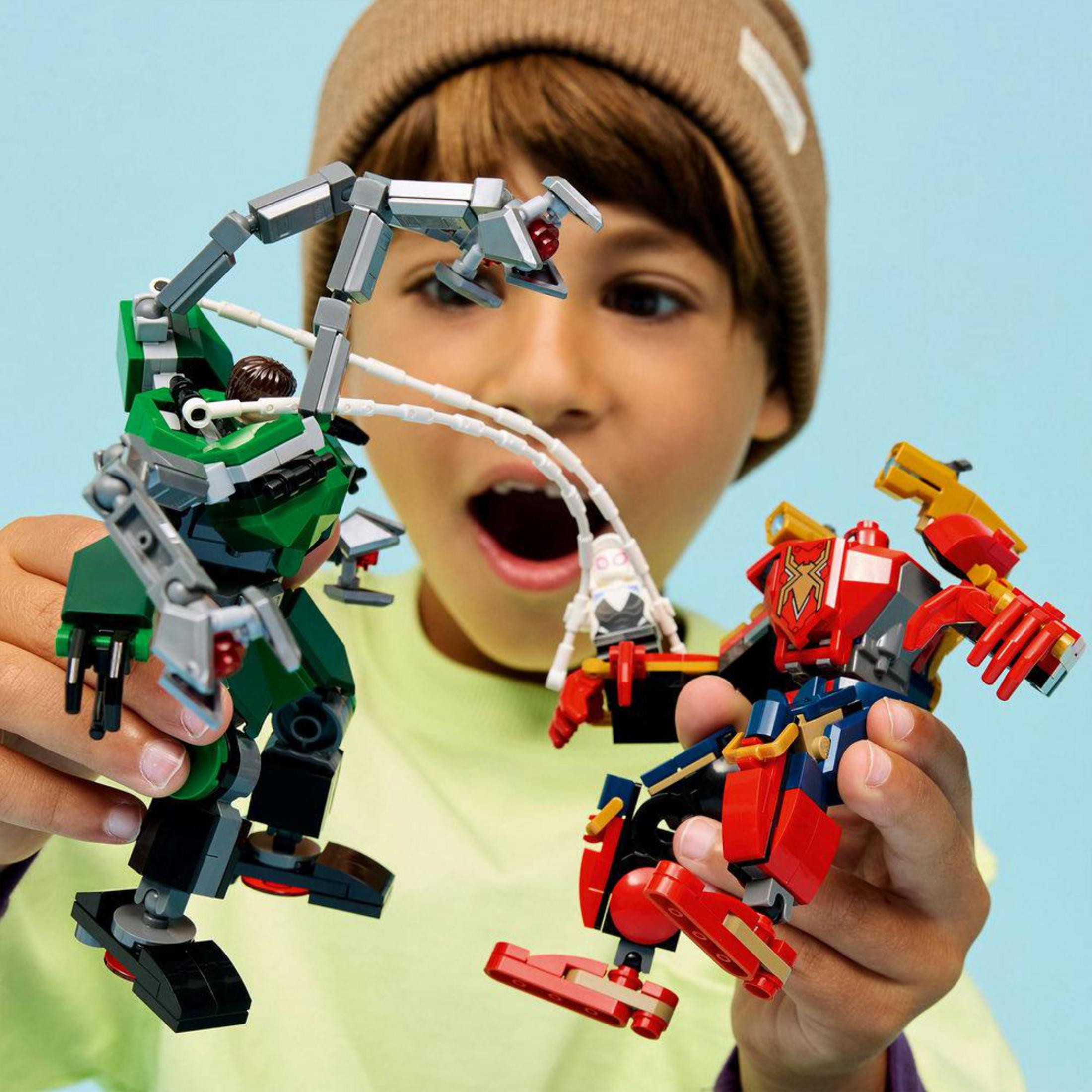 Un niño sostiene figuras de Lego: un robot verde, un robot rojo y una figura blanca.