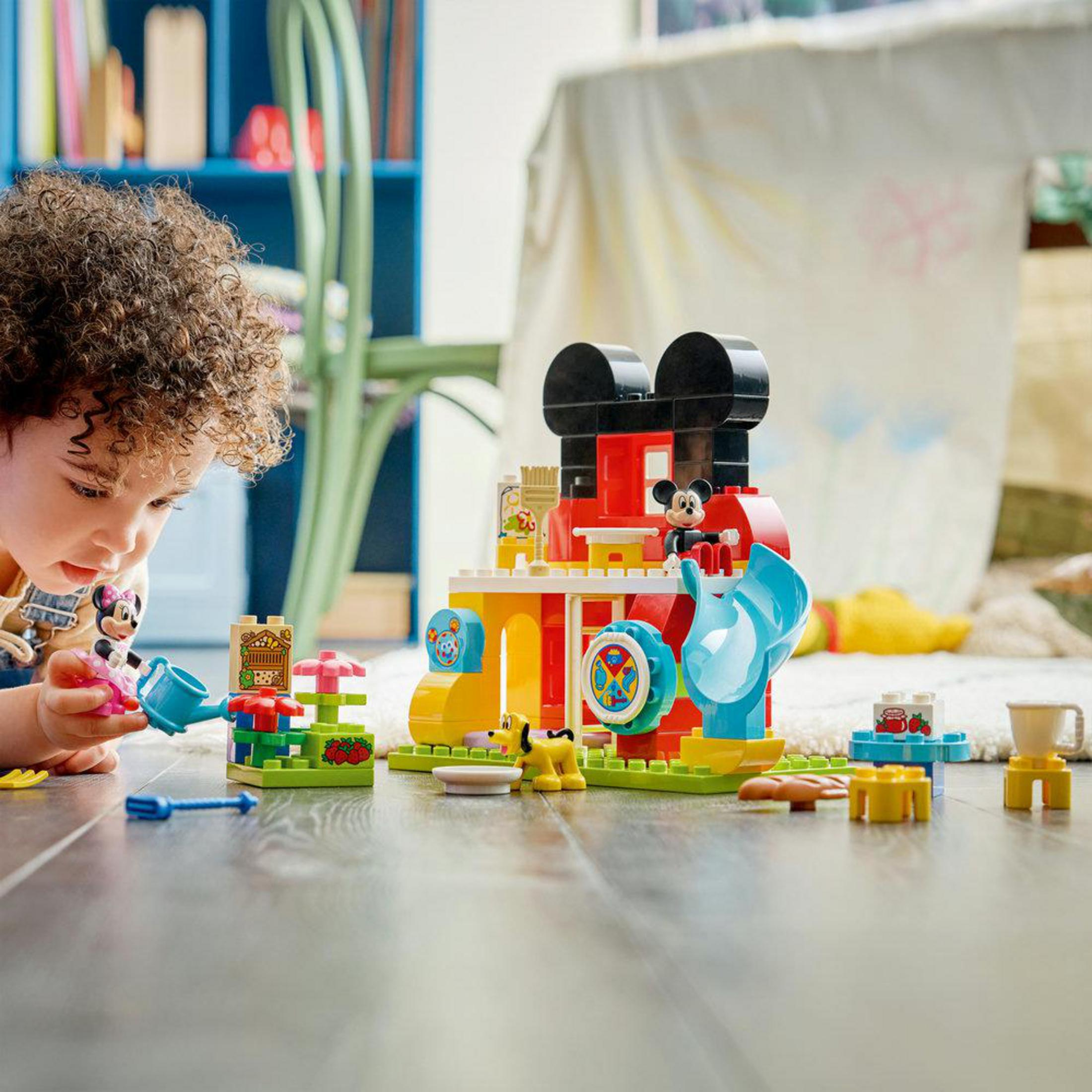Dziecko bawi się klockami Lego Myszki Miki na podłodze.