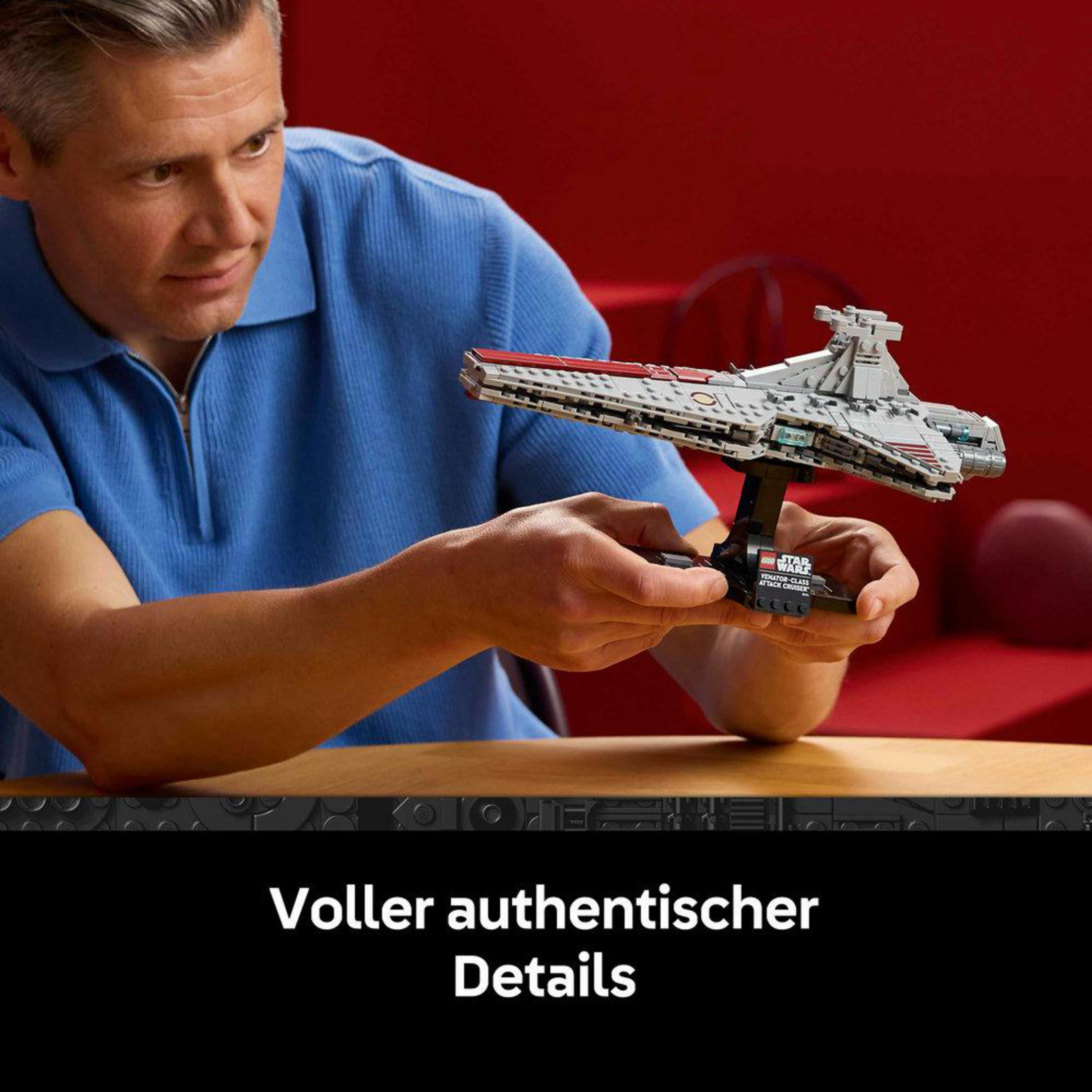 Mężczyzna trzyma szary model statku Star Wars z czerwonymi detalami.