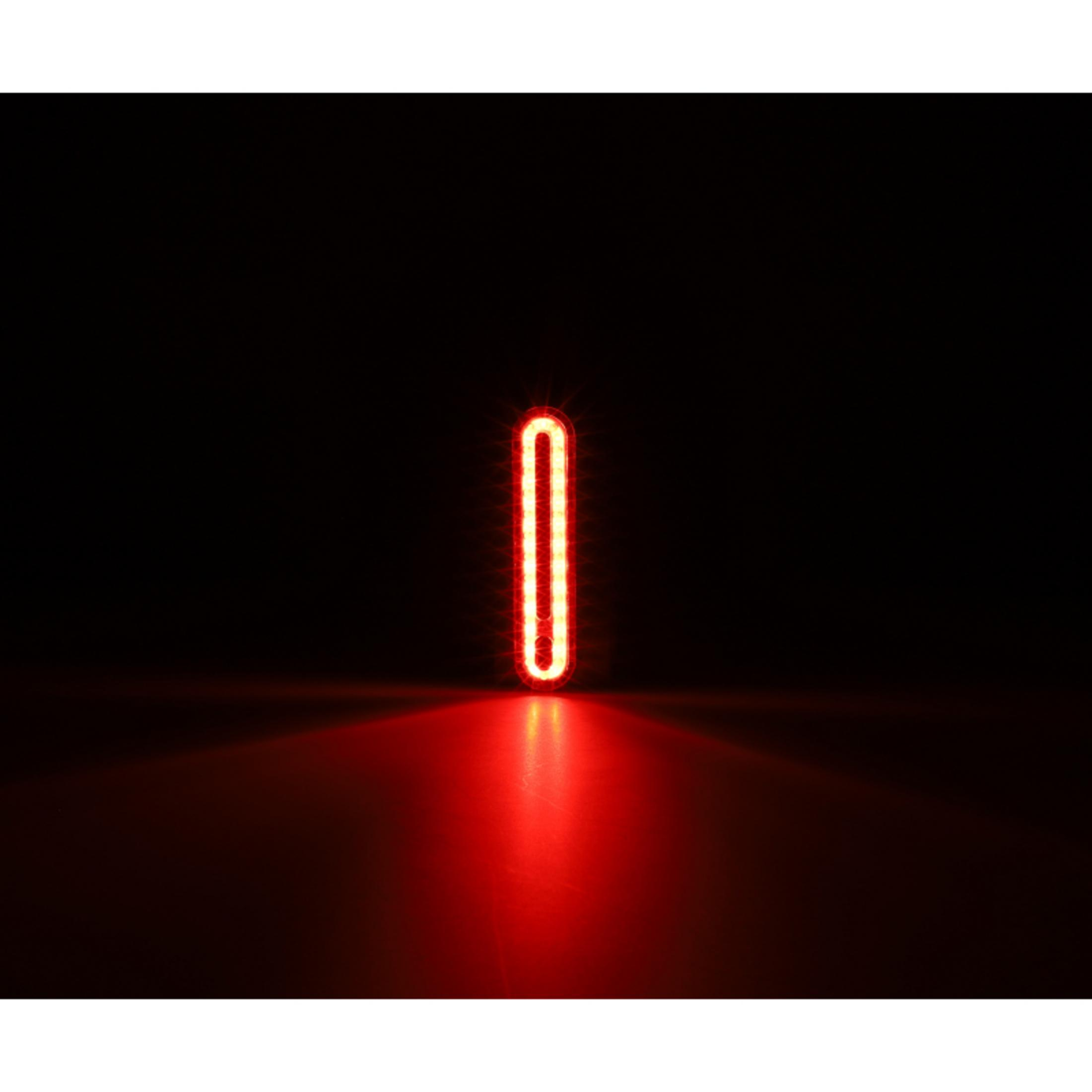 Eine vertikale, ovale rote LED-Leuchte mit dunklem Hintergrund und Lichtreflexion.