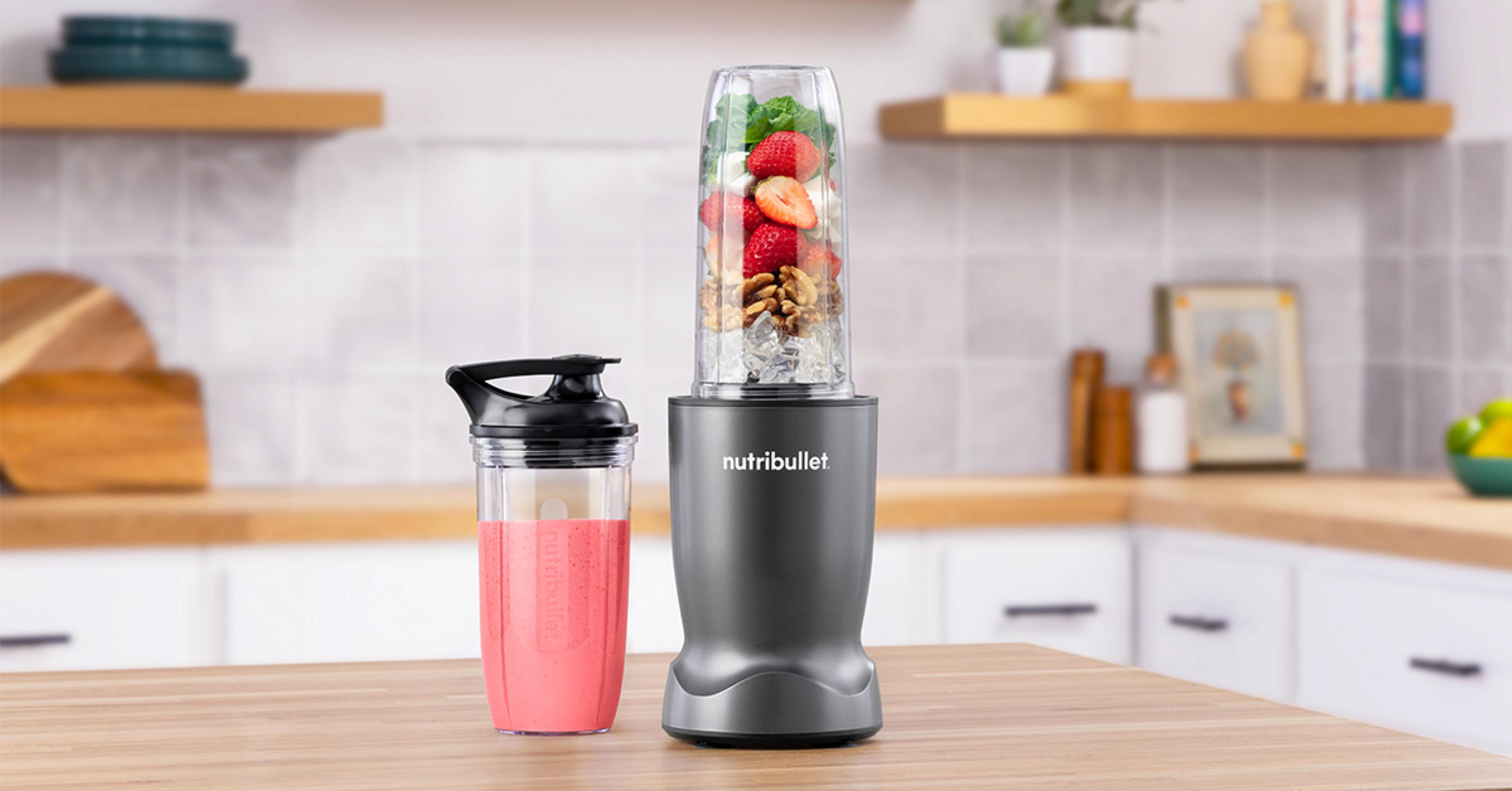 Ein grauer Nutribullet Mixer mit einem Becher mit Erdbeeren und Nüssen.