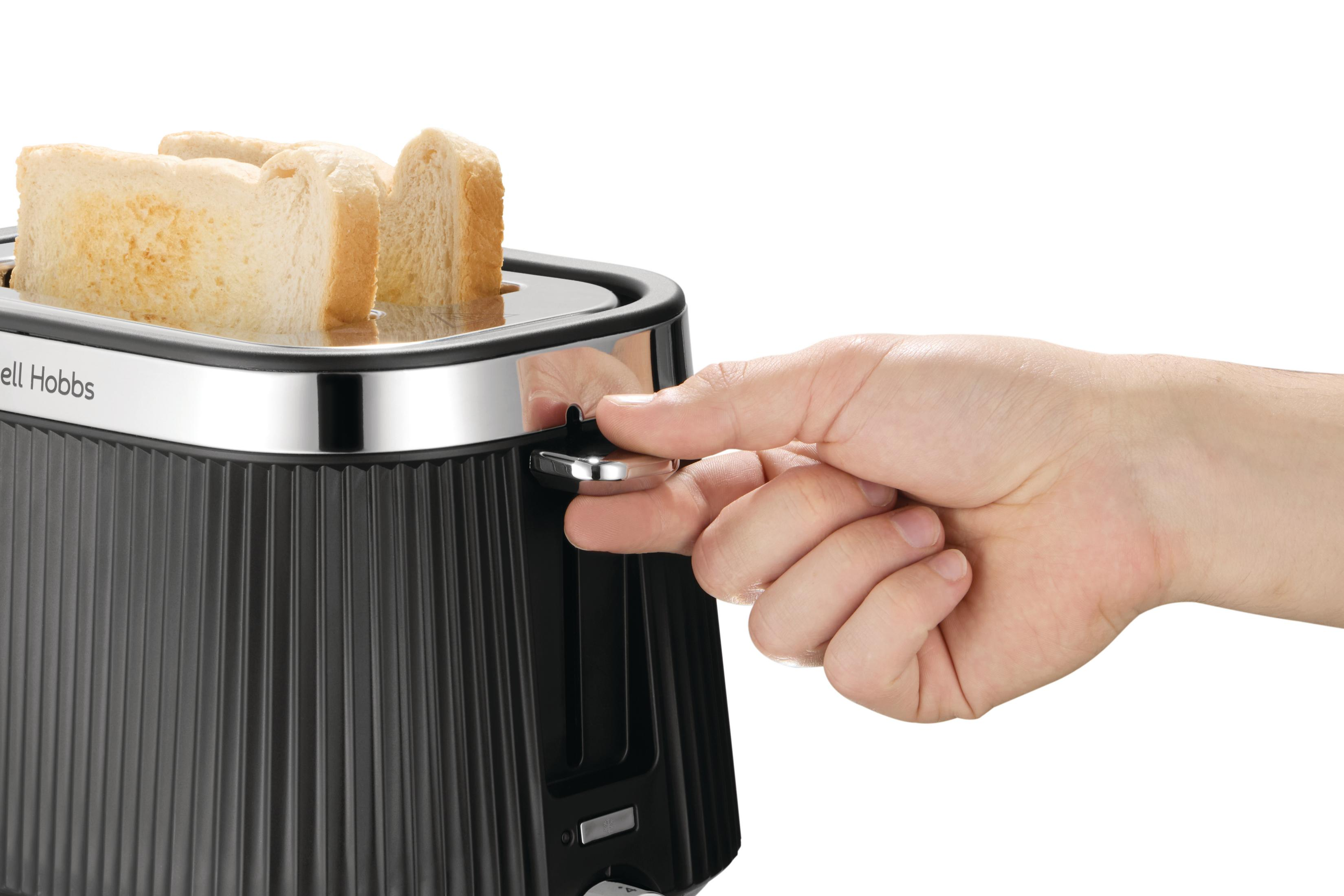 Una mano regola la leva di un tostapane nero con fette di pane.