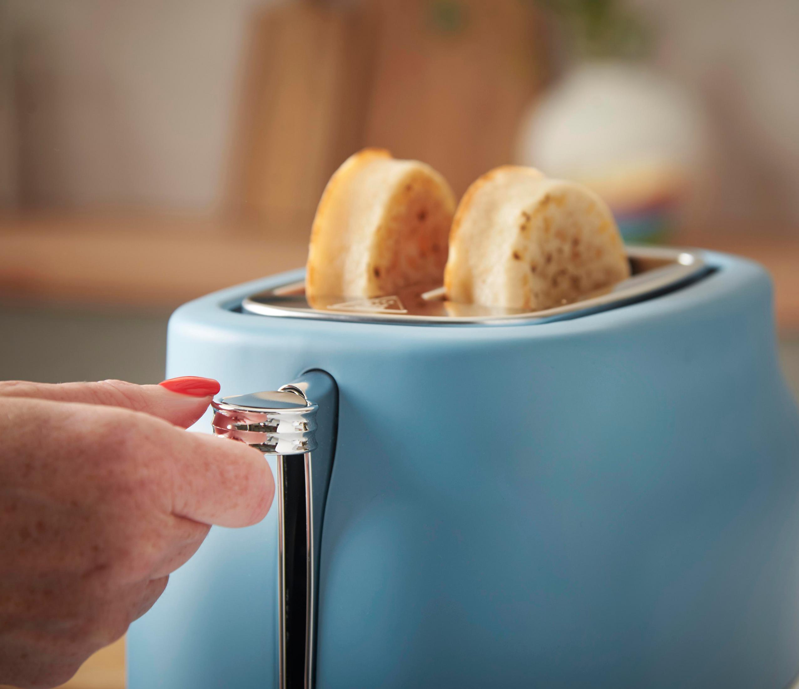 Blaue Toaster mit zwei Toastbrotscheiben, die von einer Hand mit rotem Nagellack bedient werden.