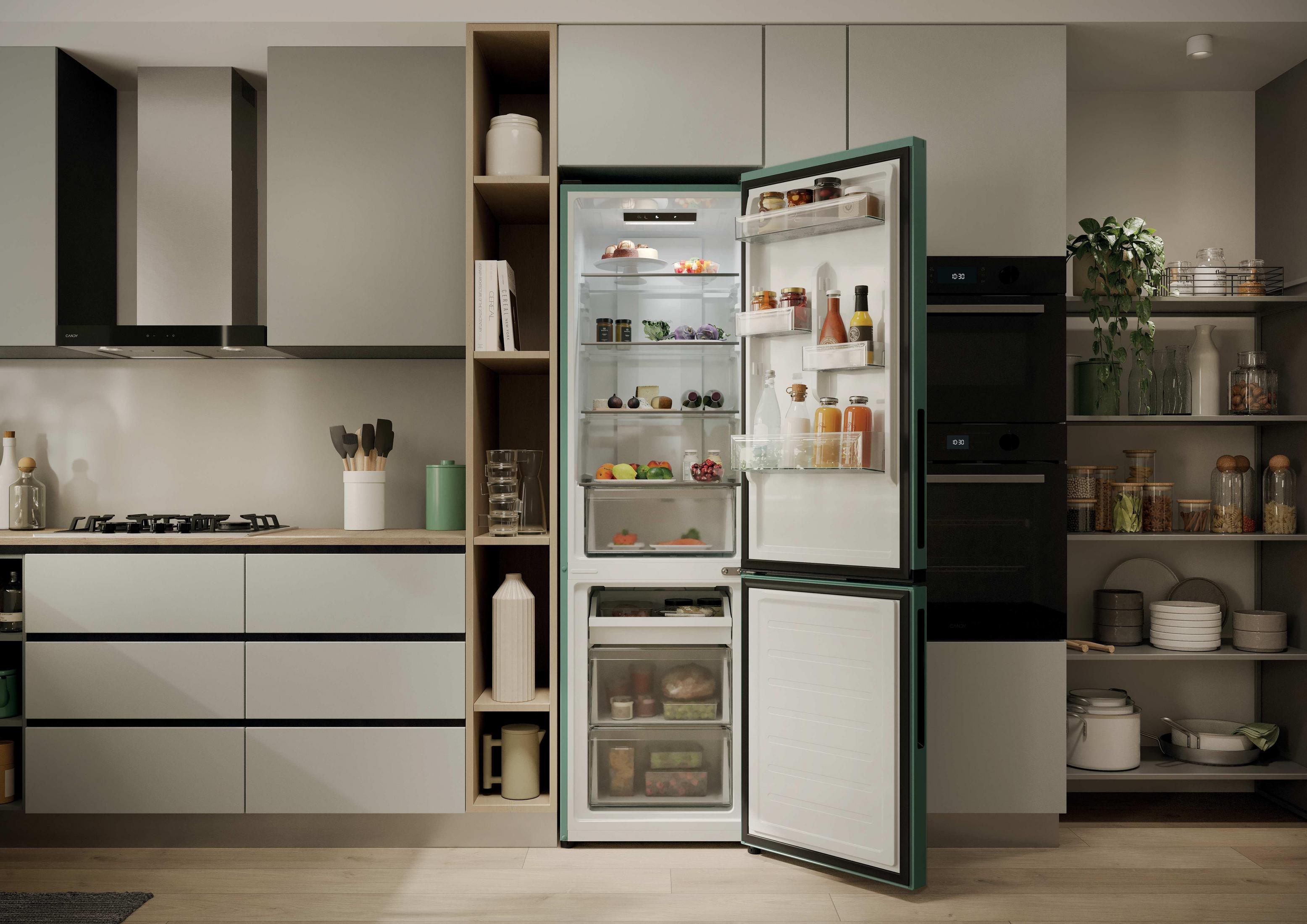 La porta verde di un frigorifero da cucina è aperta, mostrando scaffali pieni. Forni e scaffali della dispensa sono nelle vicinanze.
