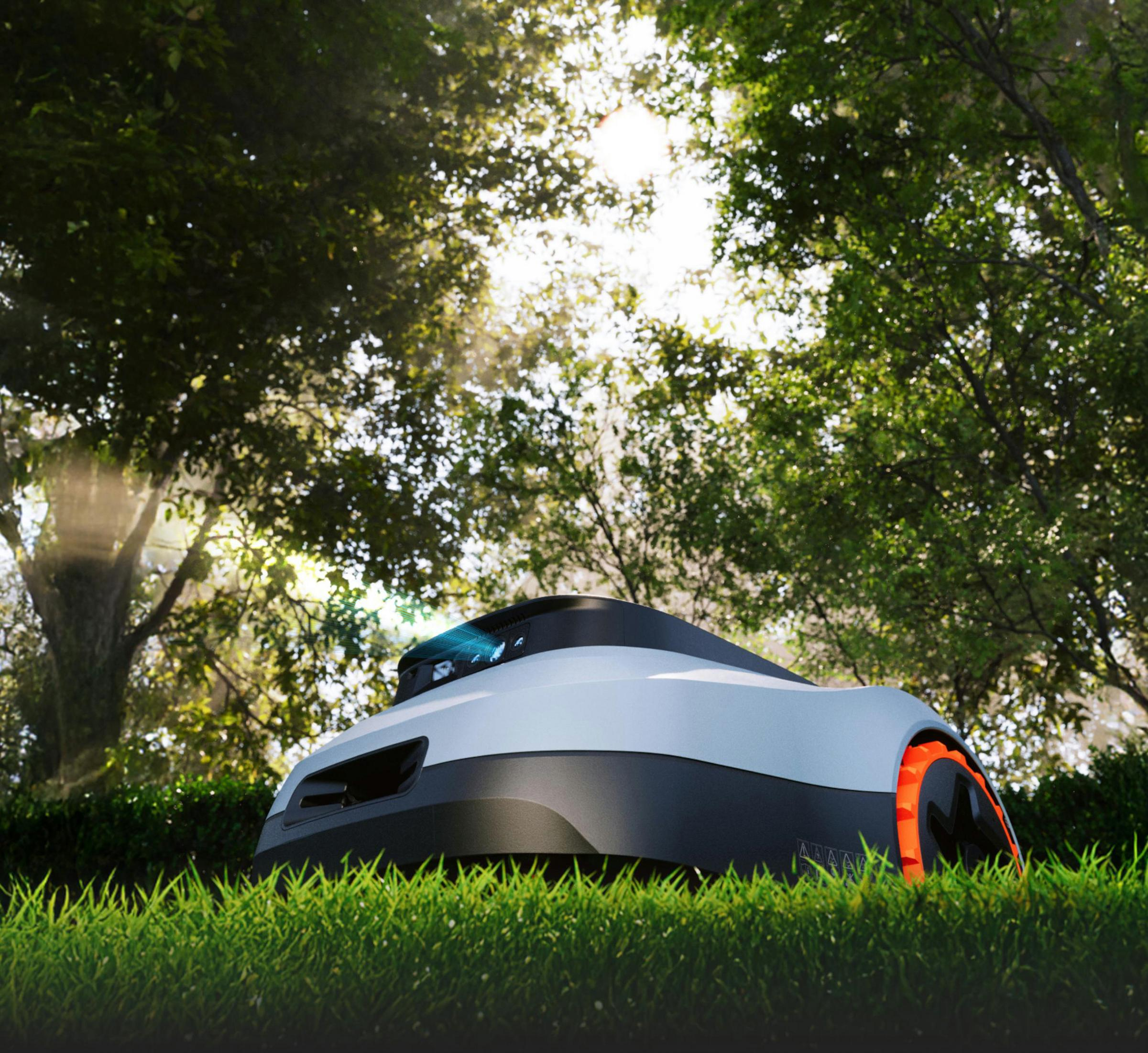 Ein Mähroboter steht auf einem grünen Rasen im Sonnenlicht. Bäume im Hintergrund.