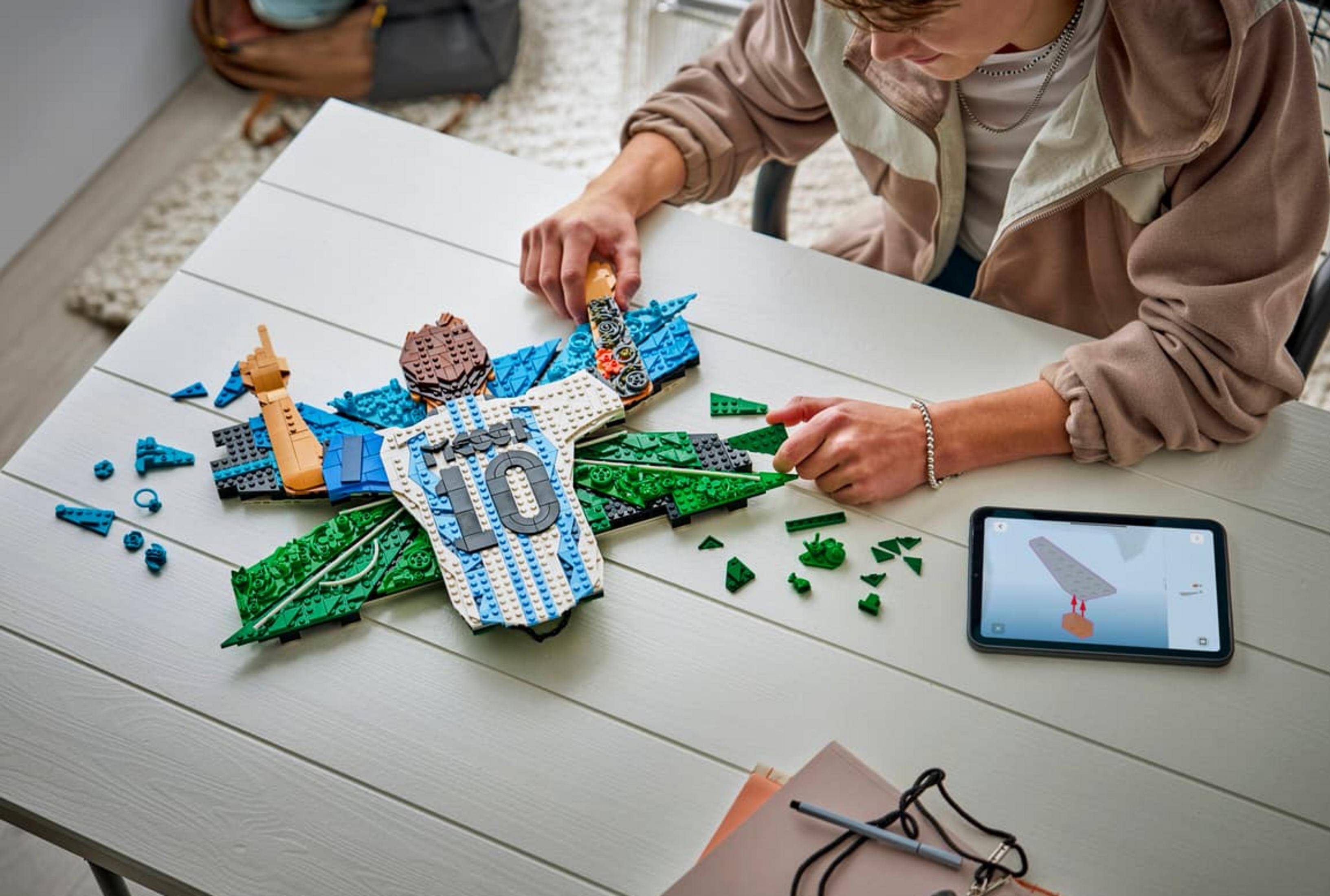 Bir çocuk masada 10 numaralı futbol forması Lego modelini inşa ediyor.