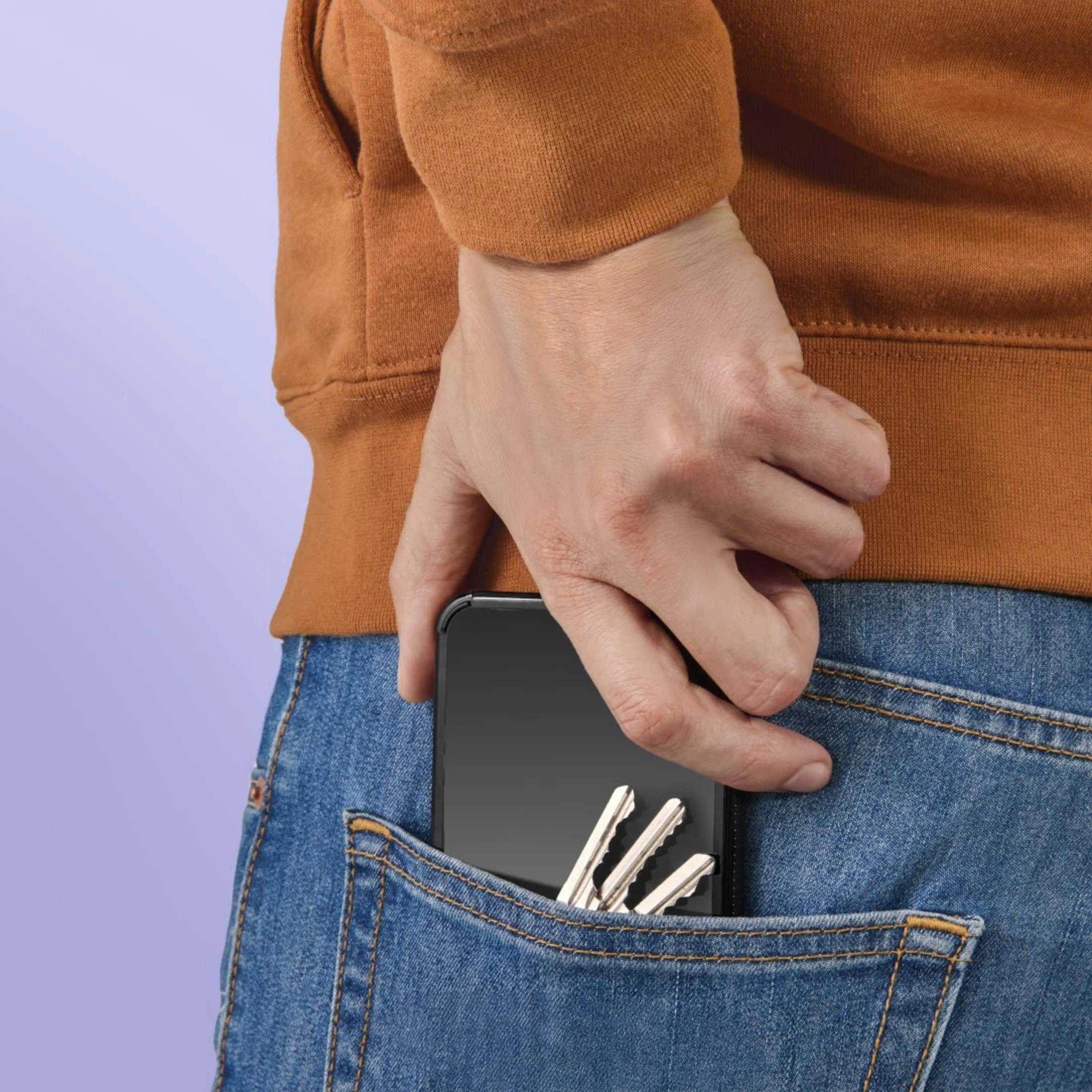 Eine Hand steckt ein Smartphone und Schlüssel in die Hosentasche.