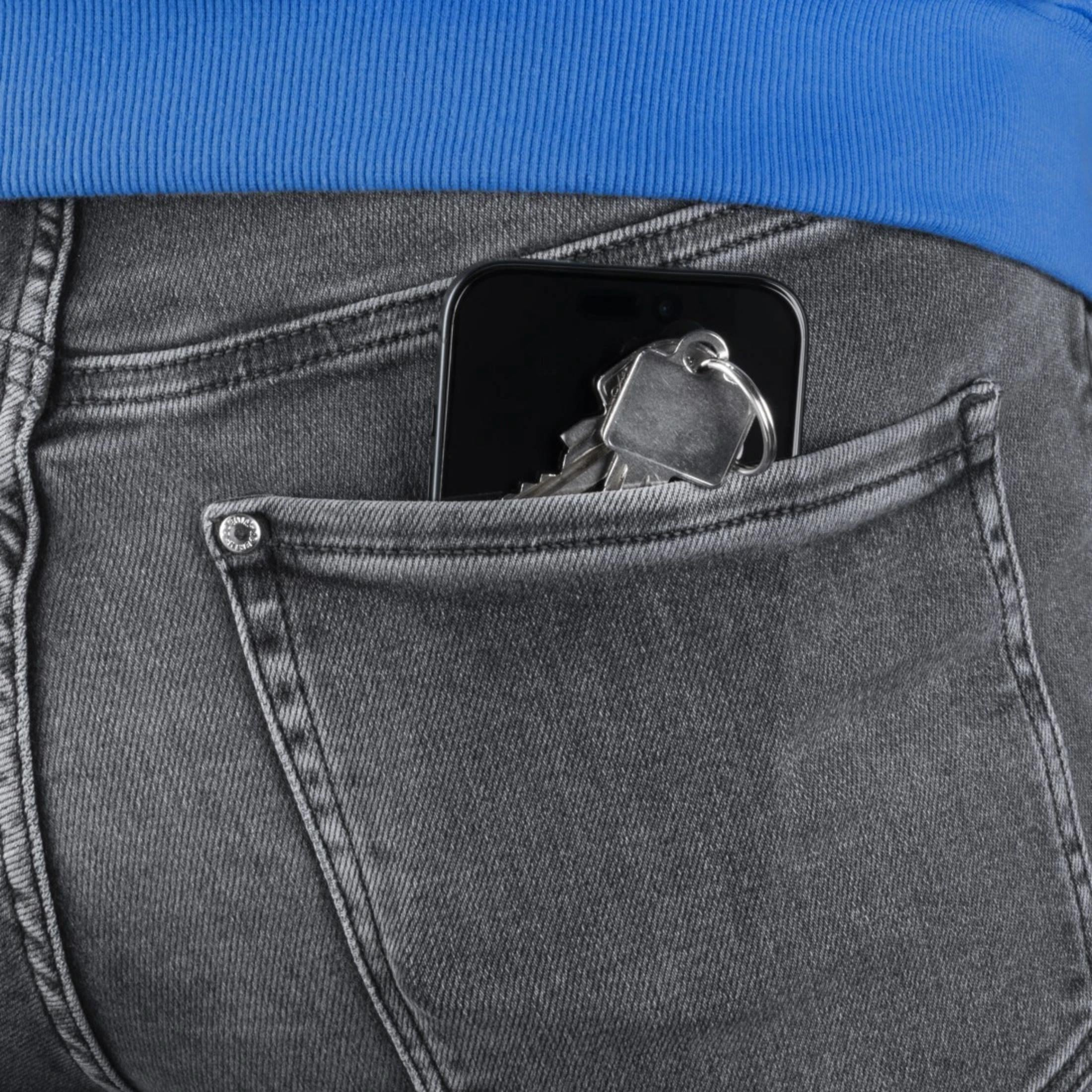 Smartfon i klucze w szarej kieszeni jeansów.