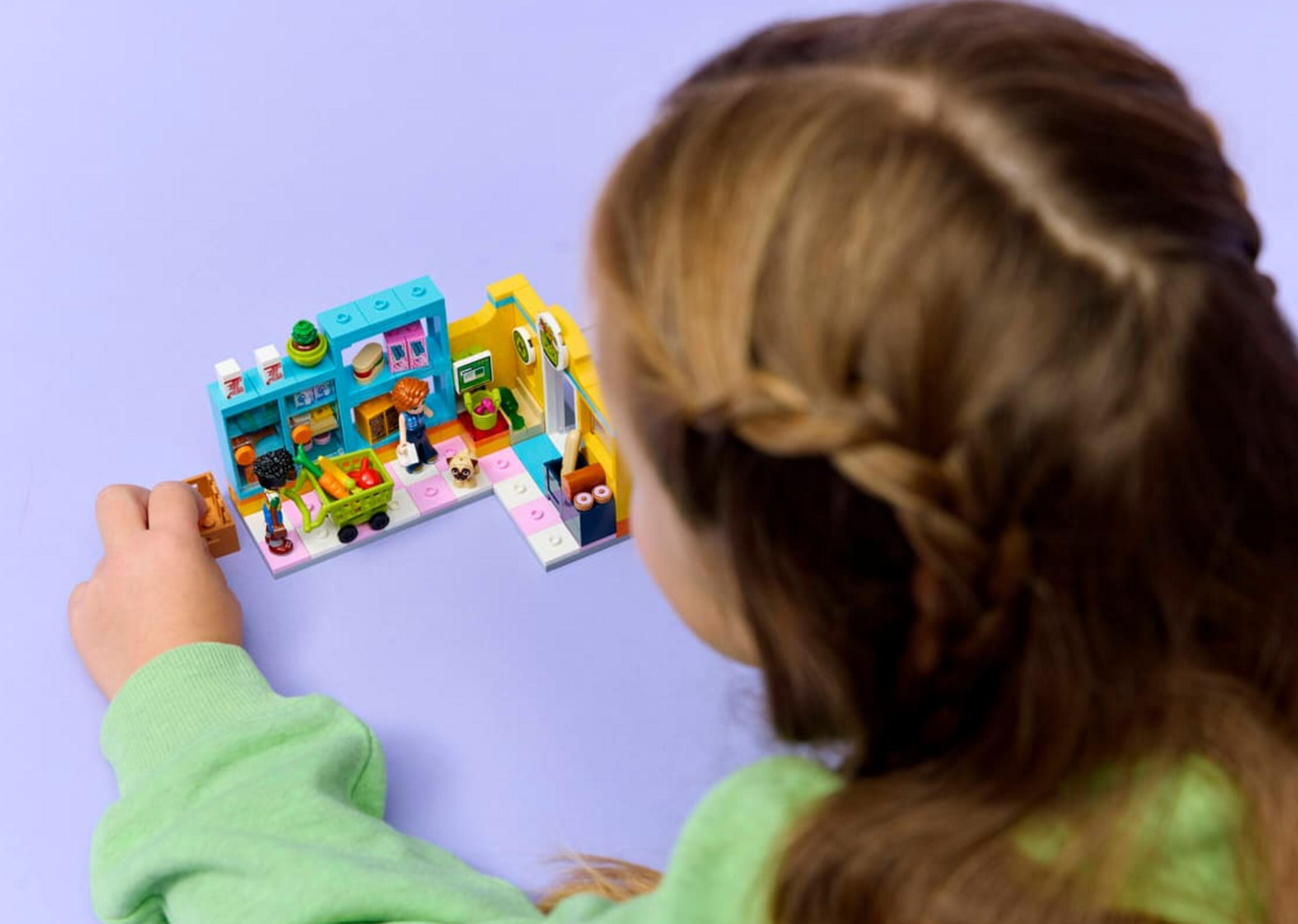 Un bambino gioca con un negozio Lego, con personaggi, generi alimentari e carrello.