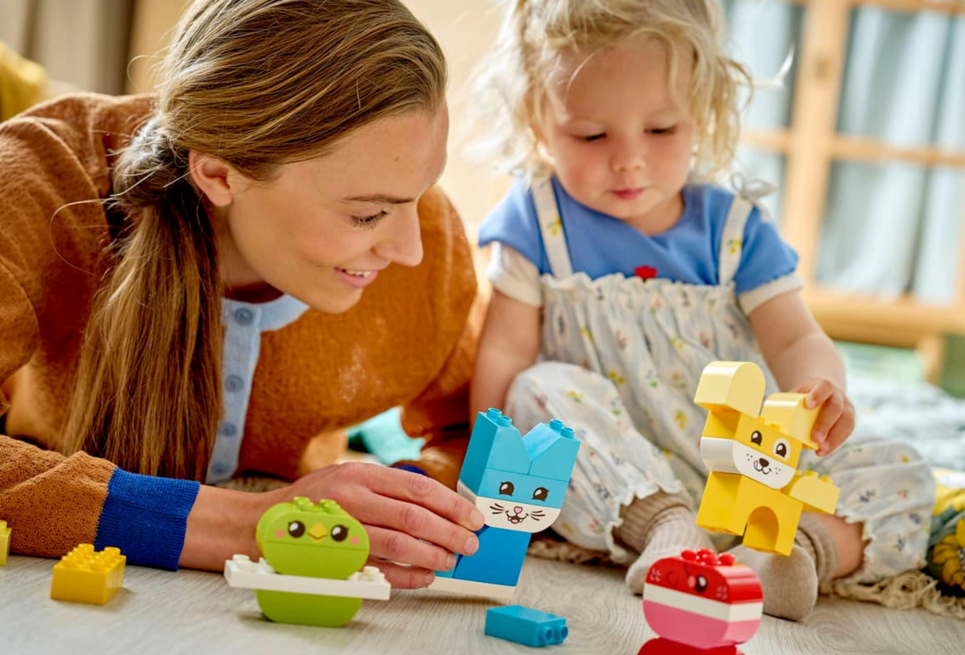Una donna e un bambino giocano con blocchi da costruzione Lego colorati a forma di animali.