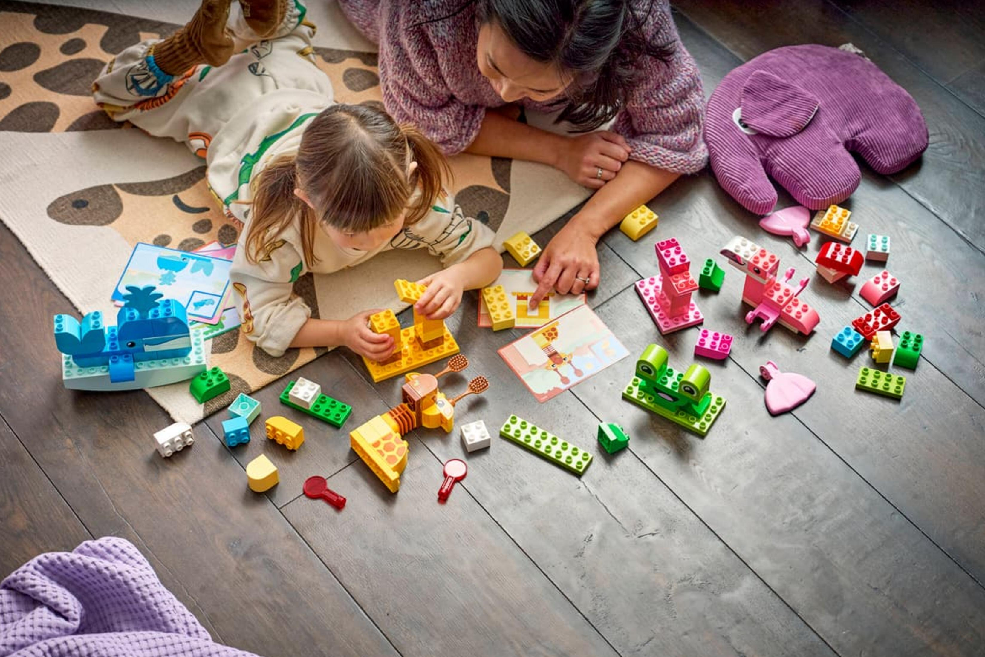 Madre e figlio giocano con blocchi Duplo colorati su un tappeto.