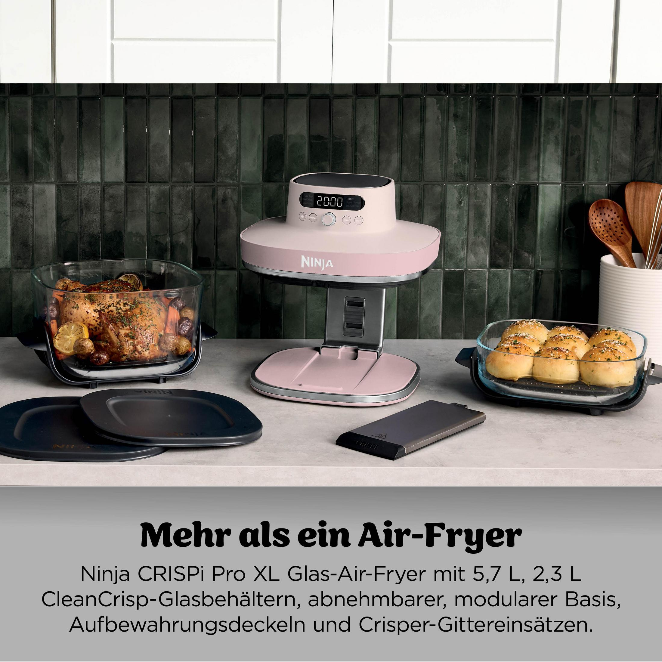 Un air fryer Ninja rose avec poulet, petits pains et ustensiles de cuisine.