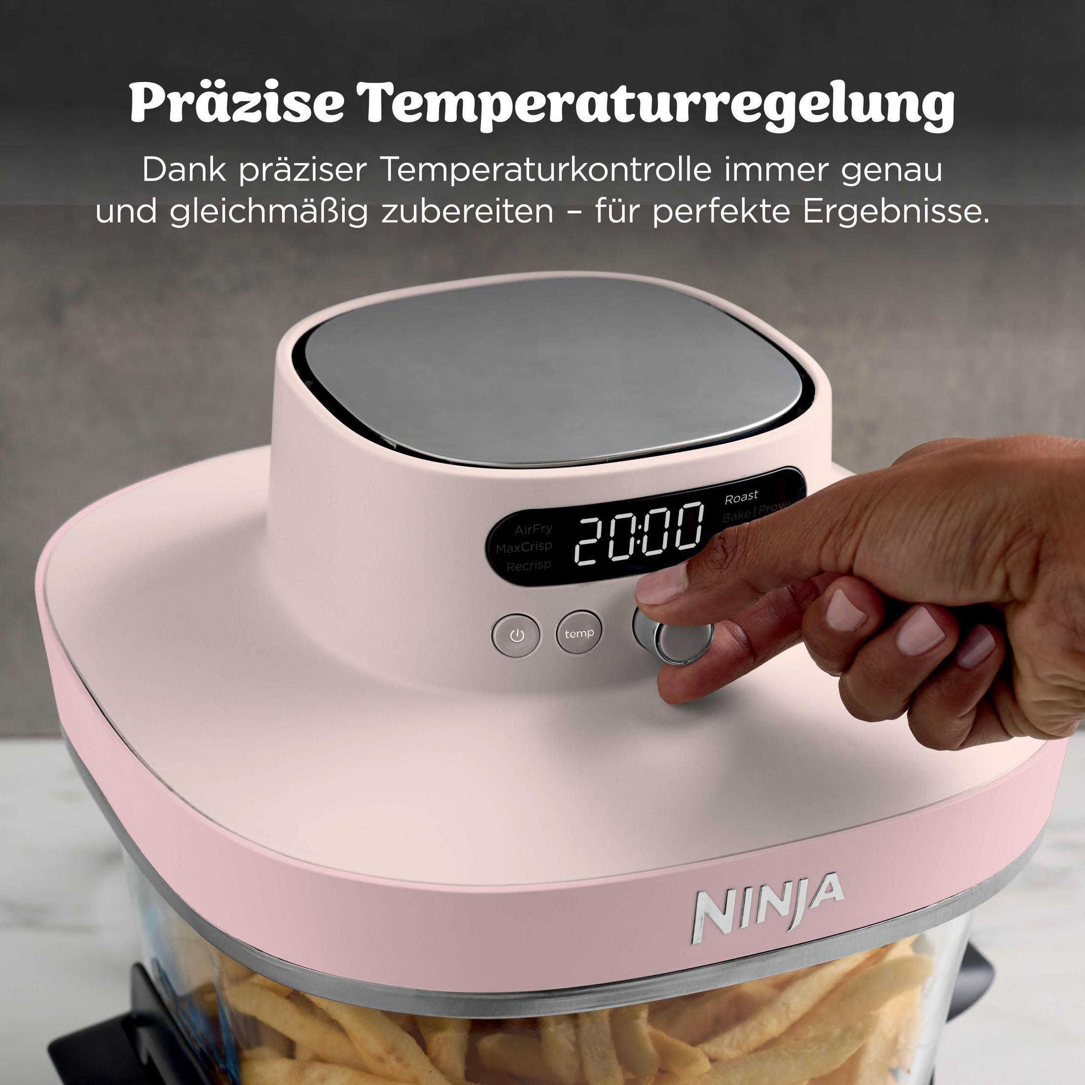 Une main ajuste une friteuse à air Ninja rose avec des frites à l'intérieur.